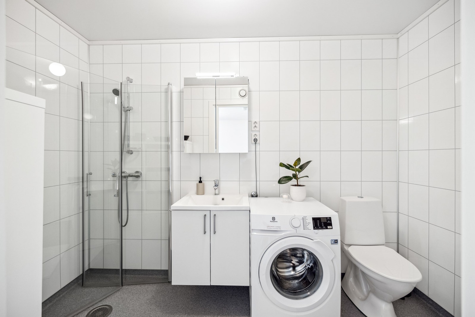 Romslig bad med gulvvarme, toalett, dusjvegger, enkel baderomsinnredning og opplegg for vaskemaskin Galleribilde