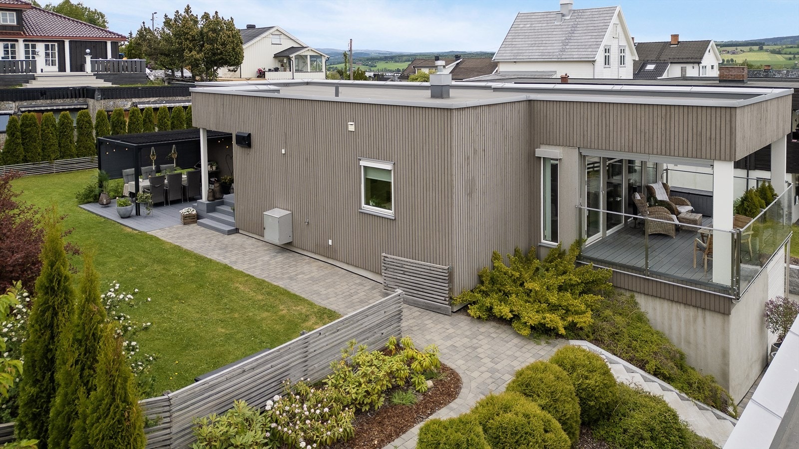 Tomten er pent opparbeidet med plen og beplanting, samt belegningsstein. Galleribilde