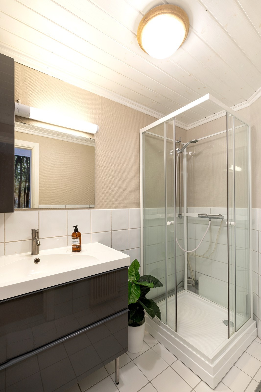 Badet har fliser på gulv og halve veggen. Galleribilde