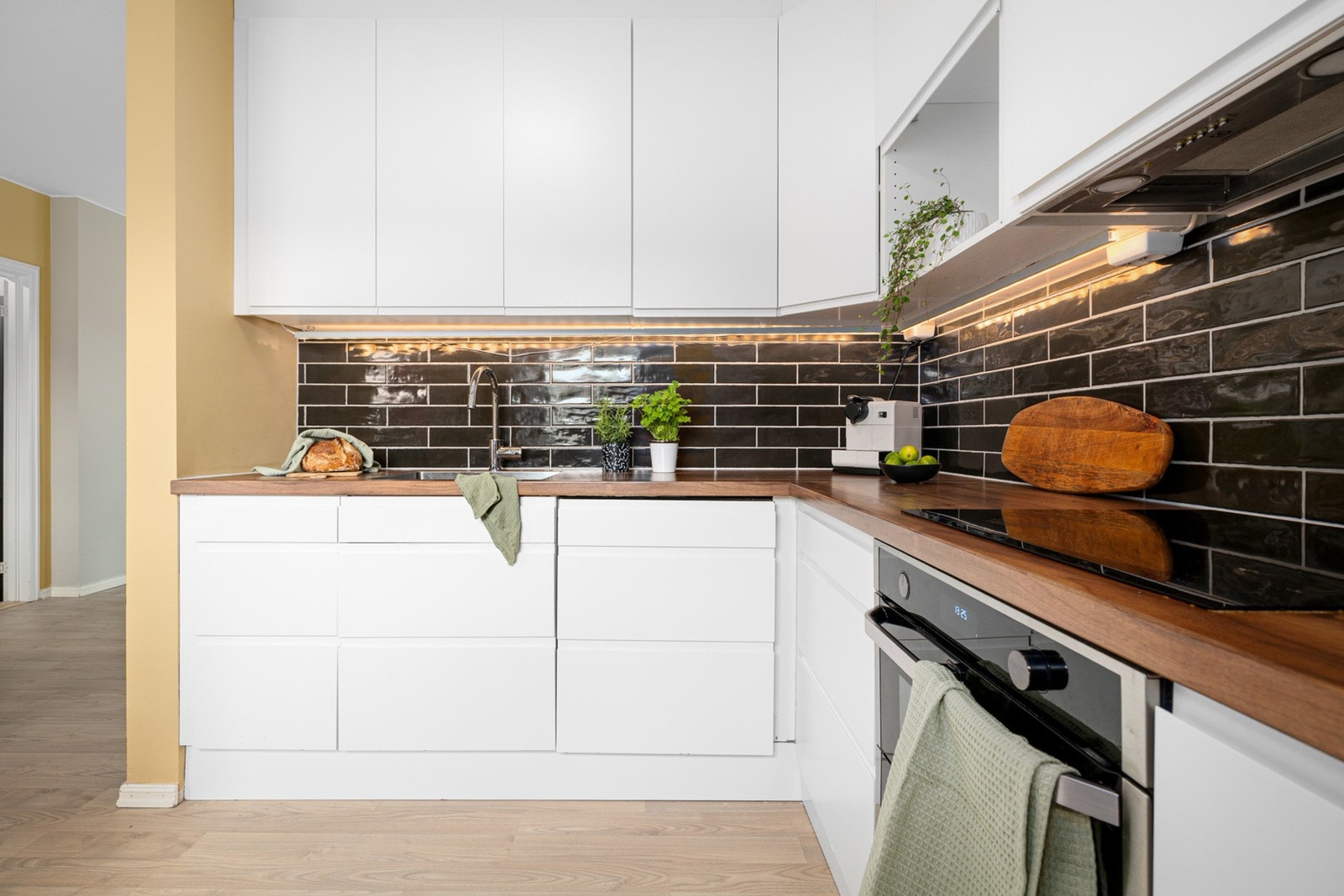 Slette fronter, laminert benkeplate, belysning og stilige fliser over benk. Galleribilde