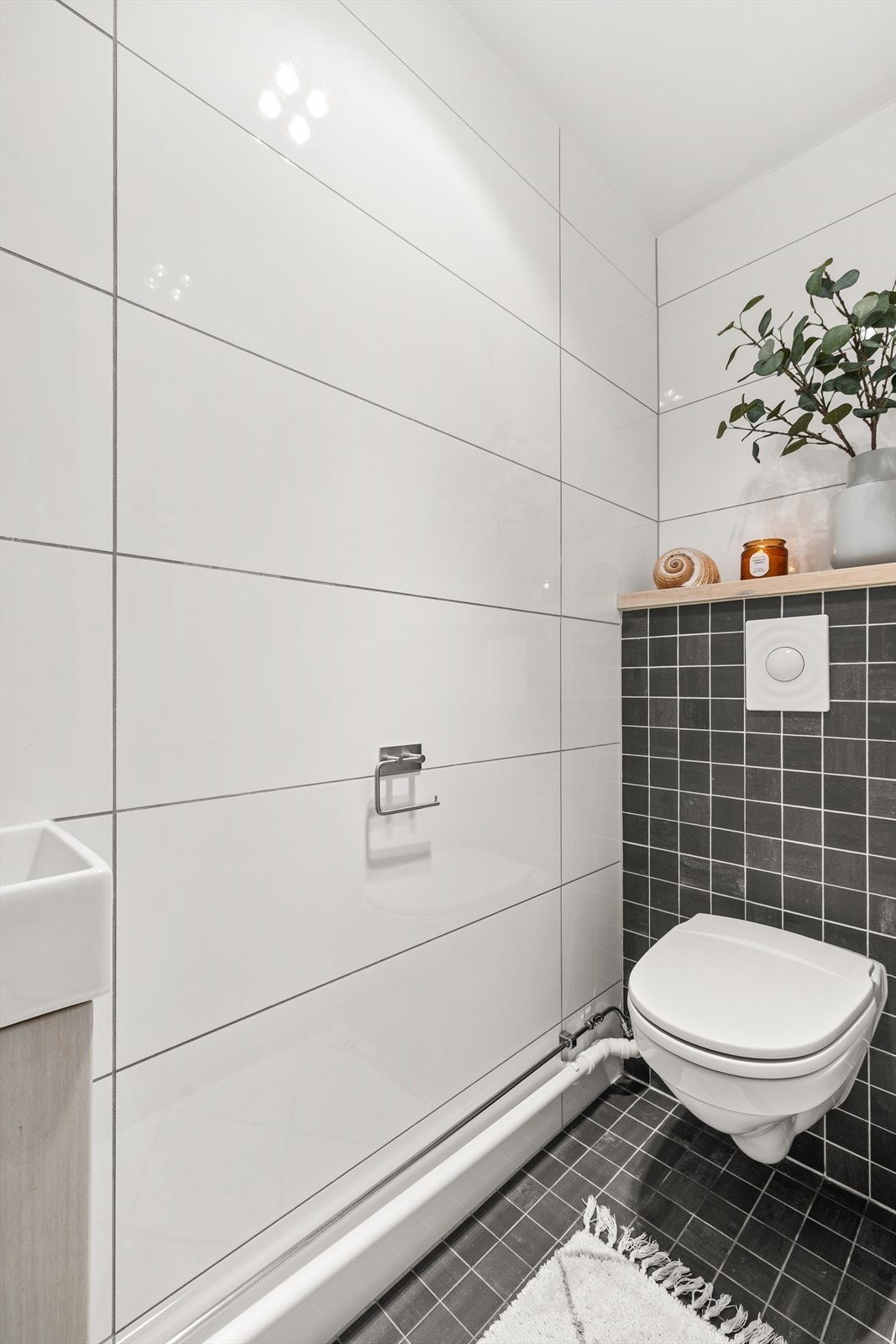 Separat toalettrom med varmekabler i gulv, vegghengt toalett og servant Galleribilde