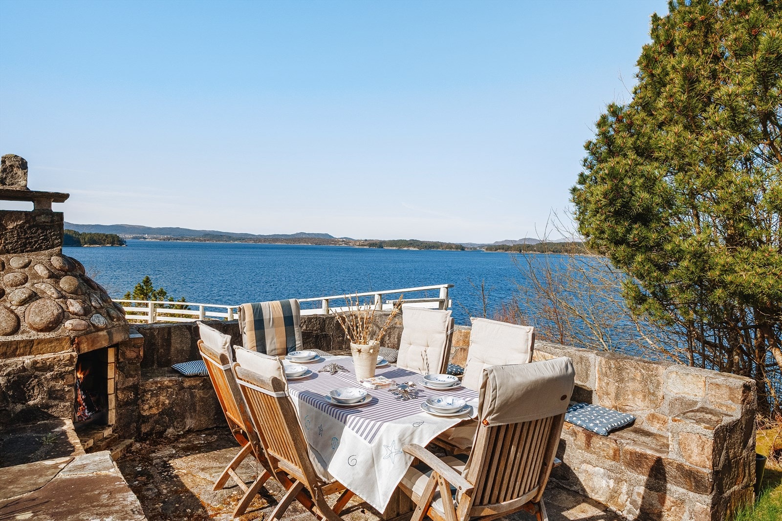 Her er det duket for hyggelige sammenkomster. Forseggjort terrasse med utepeis og benker i flott steinmur. Galleribilde