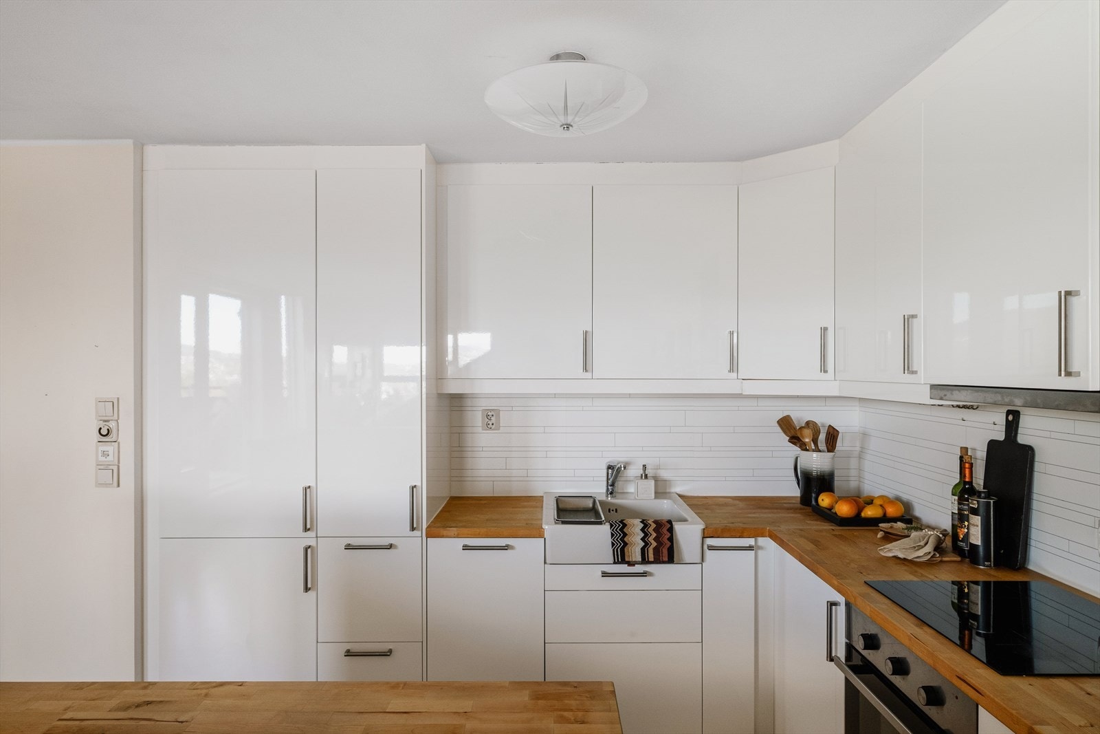 Hvit høyglans Ikea innredning med kitchenboard over heltre benkeplate. Galleribilde