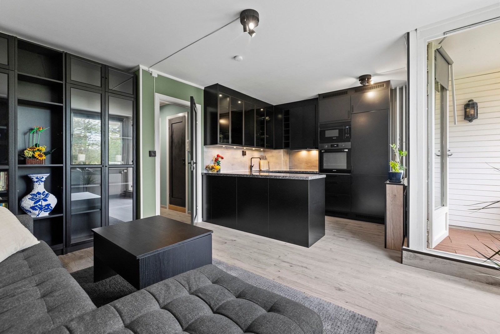 har har du en praktisk åpen stue- og kjøkkenløsning med moderne, svarte kjøkkeninnredninger Galleribilde