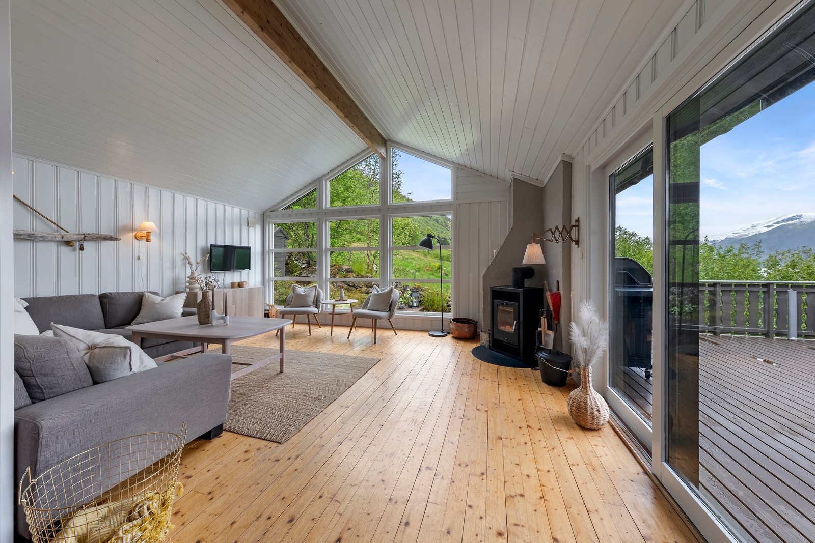 Stue med lakkert tregulv, panel i tak og vegger. God takhøyde Galleribilde