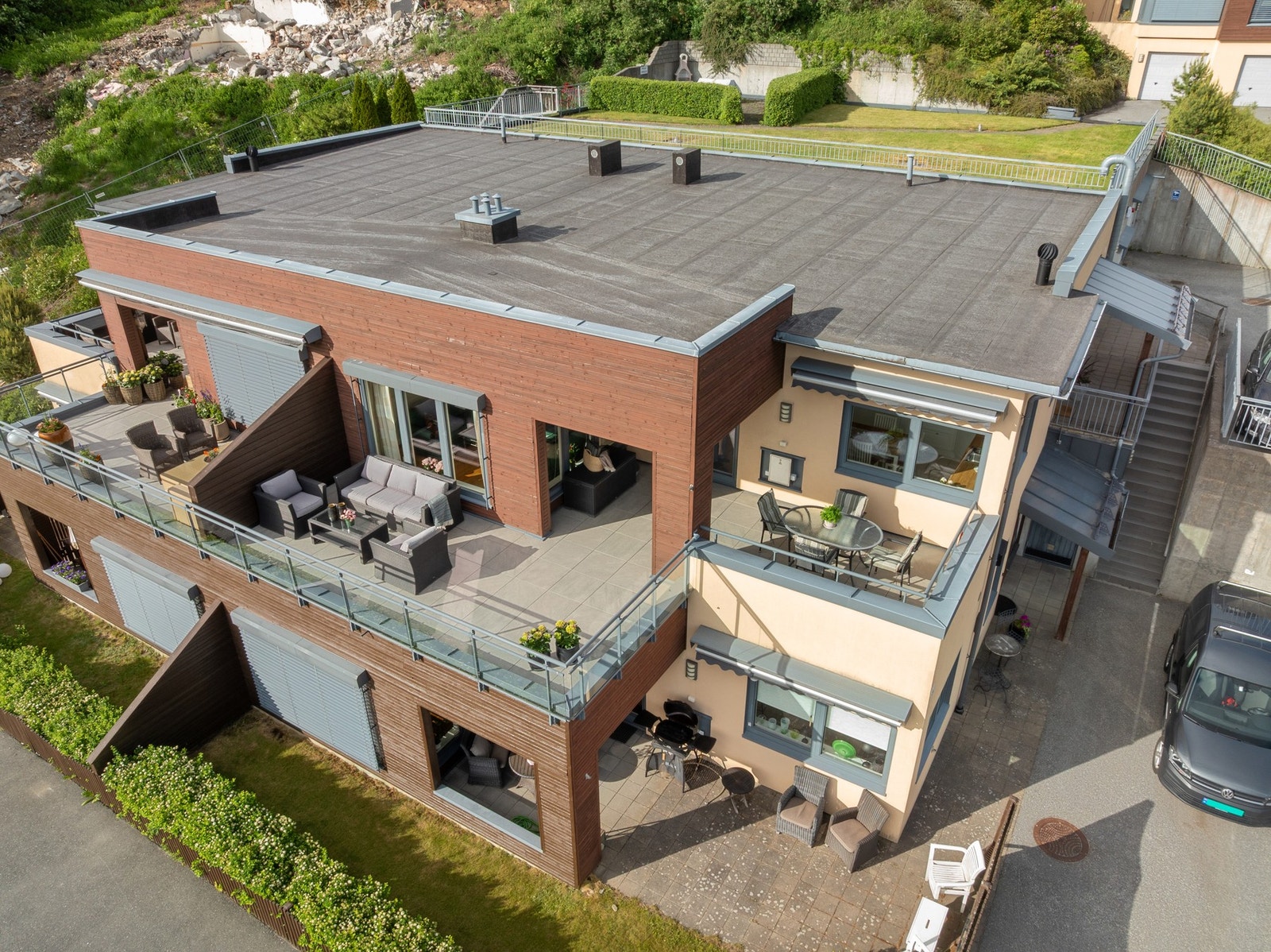 Terrassen er romslig med flere soner. Noe av terrassen er og overbygget om man vil sitte i skyggen. Legg og merke til sameiets felles grillplass på taket av garasjen. Galleribilde