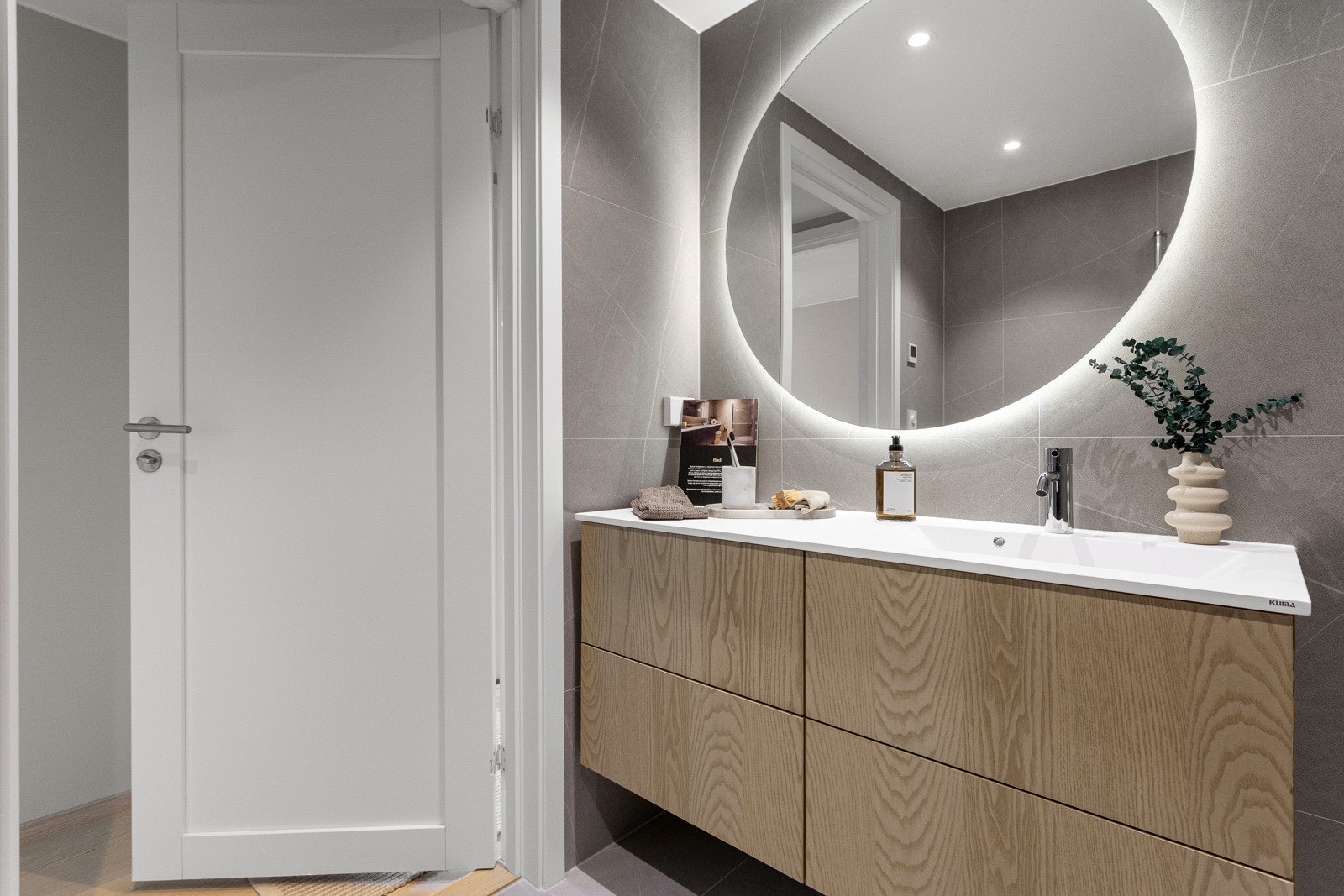 Kuma komposittvask og rundt speil med belysning. Dornbracht står for de elegante armaturene til servanten og dusjen. Galleribilde