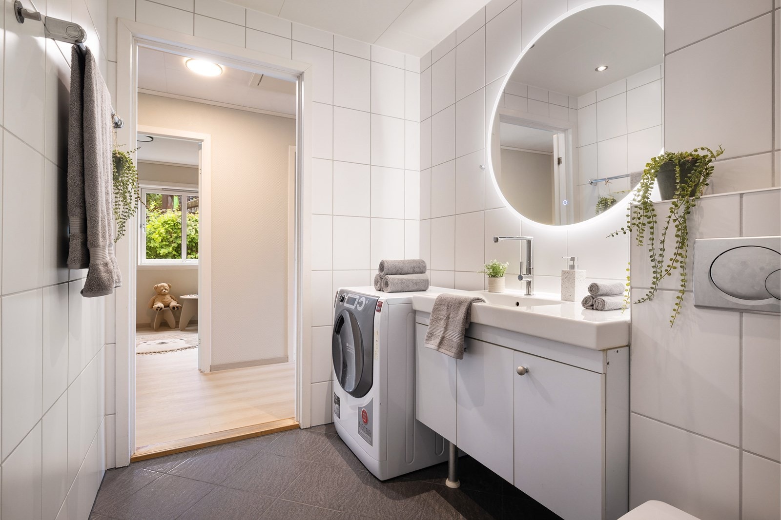 Badet er innredet med servantskap, innebygd sisterne og opplegg for vaskemaskin. Dusjsonen har glassbyggerstein og skyvedører i glass med gulvskinne. Galleribilde