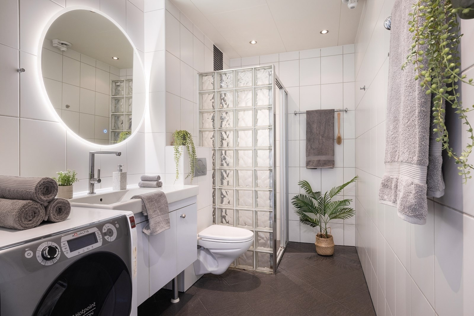 Badet er gjennomført med fliser på gulv og vegger, noe som gir et helhetlig og moderne uttrykk. Det er varmekabler i gulvet og mekanisk avtrekk. Galleribilde