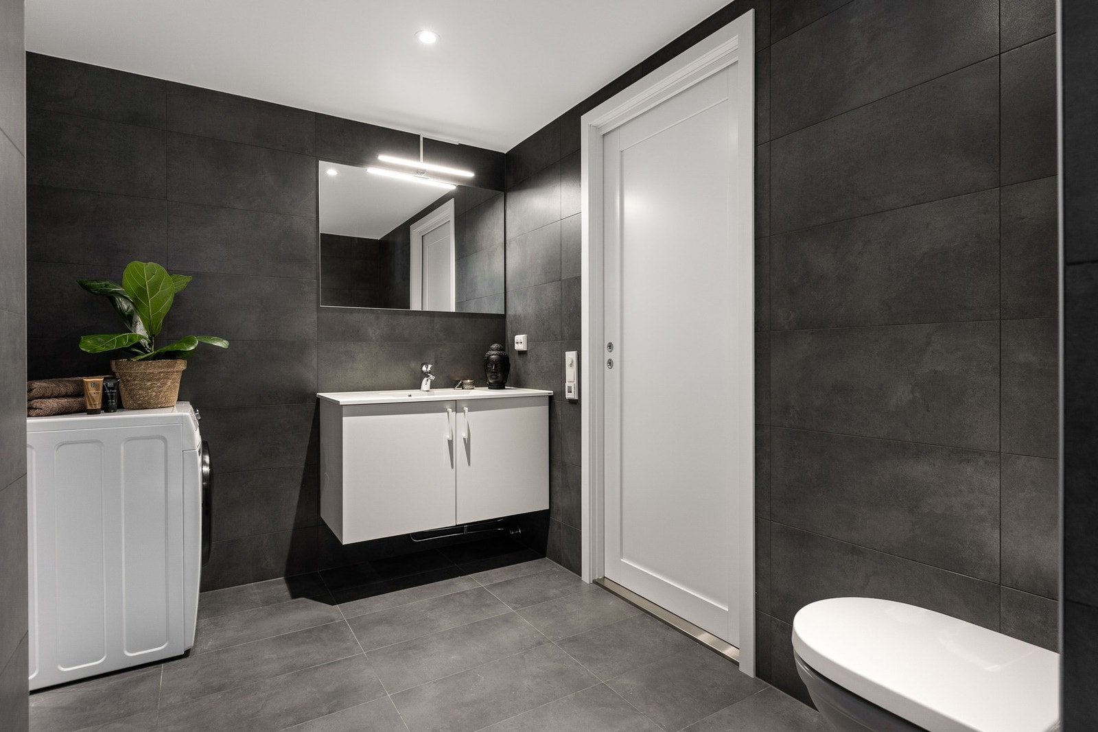 Lekkert bad med mørke, stilige fliser på gulv og vegg. Galleribilde