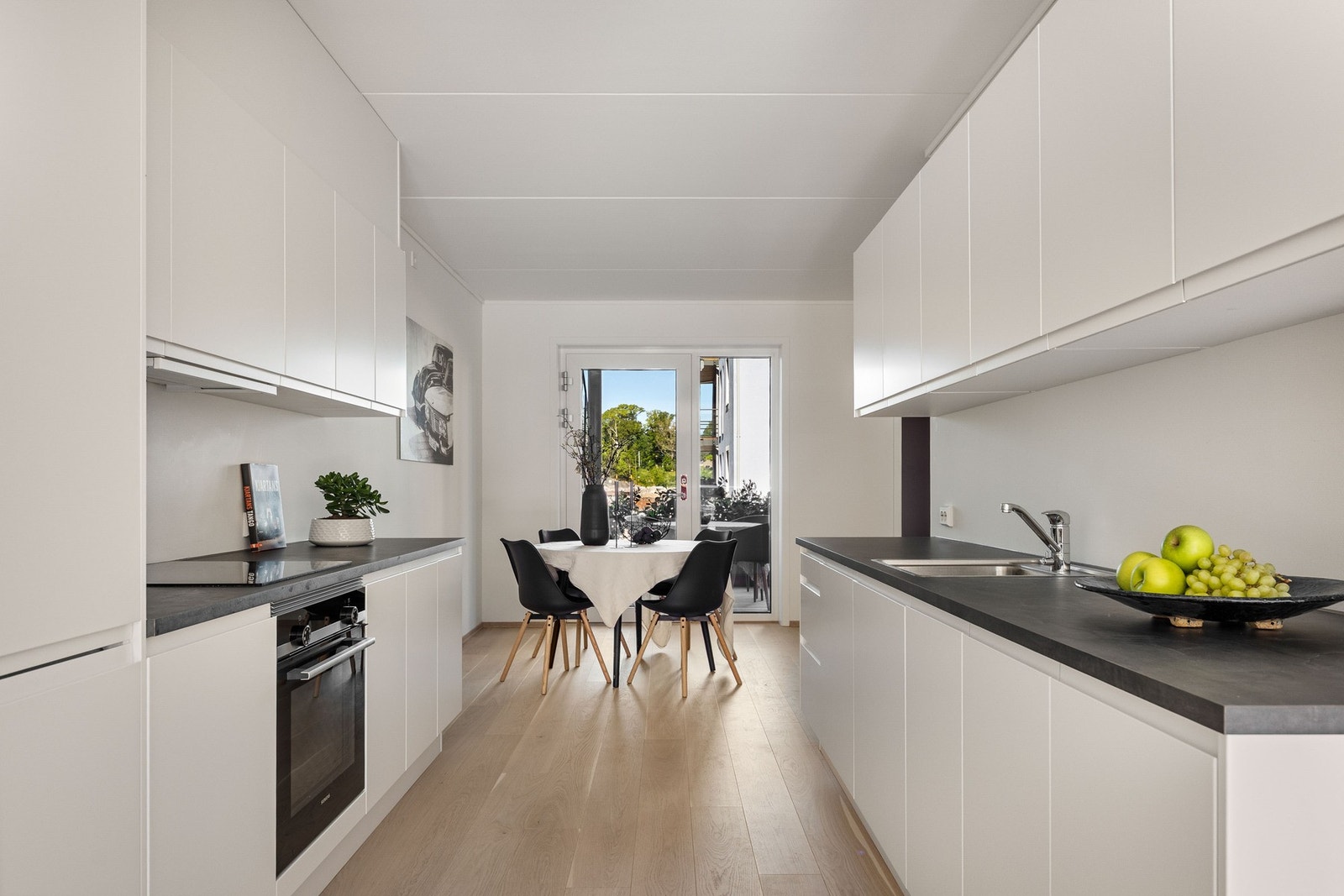 Kjøkkenet har hvite fronter med stilige, mørke benkeplater. Galleribilde