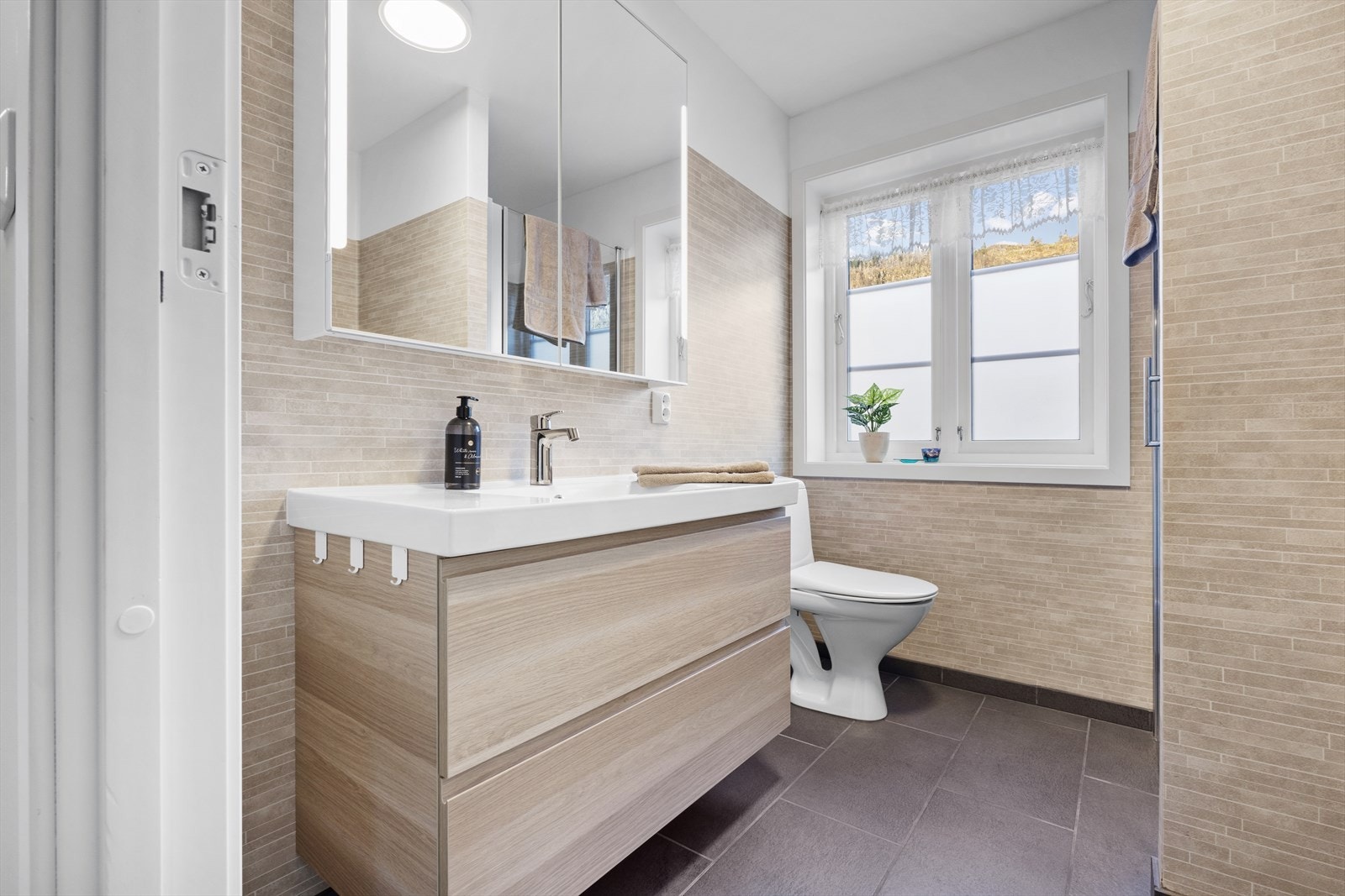 Badet har opplegg for vaskemaskin, bred servant m/underskap og speilskap over Galleribilde