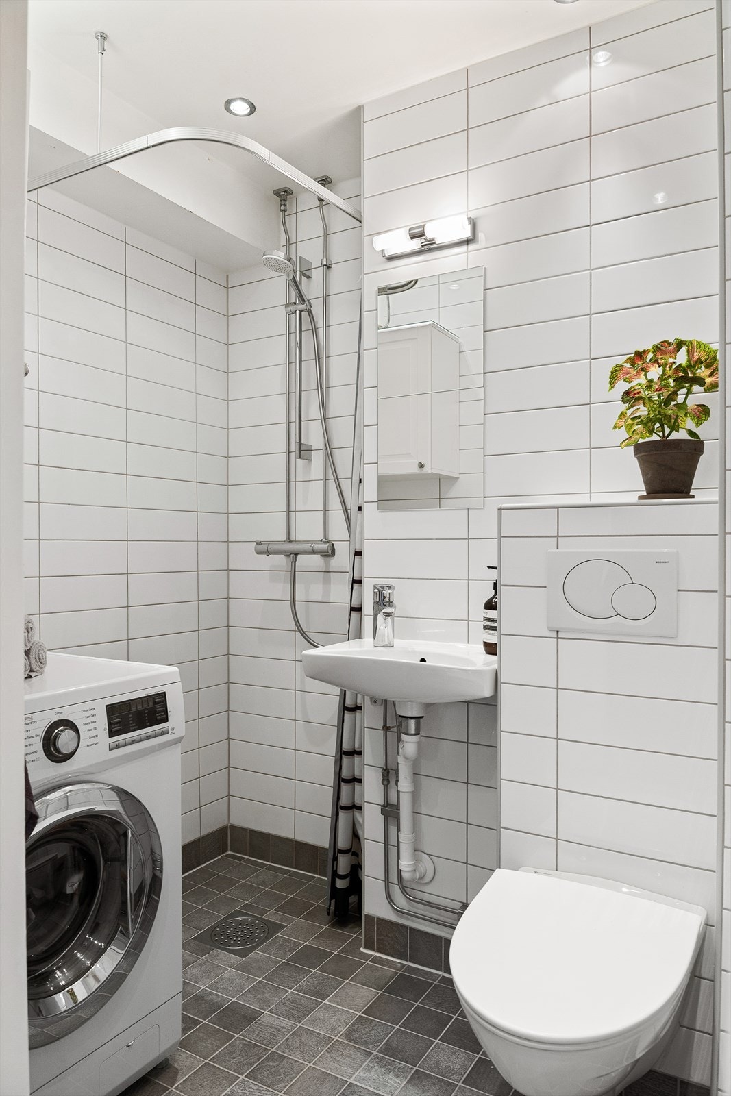 Badet ble oppusset av borettslaget i 2010 og har veggmontert WC, dusj med dører, servant med ettgreps blandebatteri og opplegg for vaskemaskin. Galleribilde