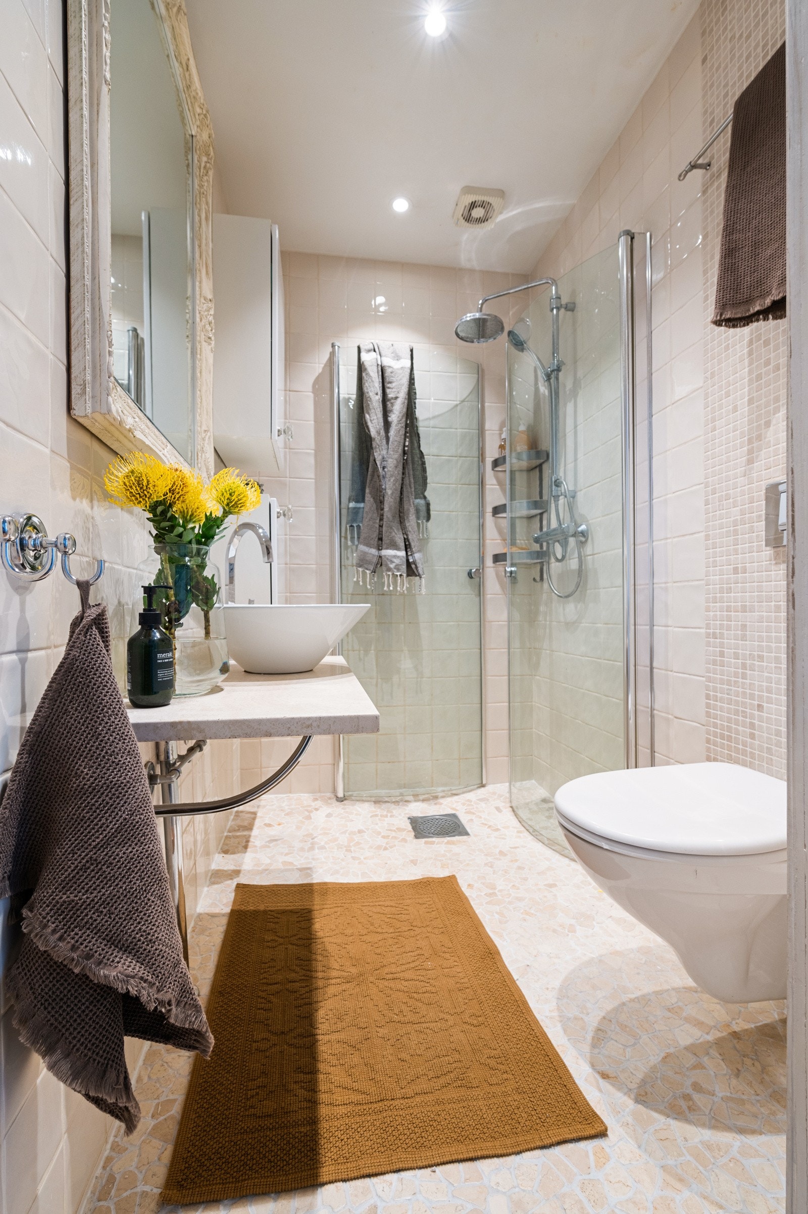 Her kombineres lyse veggfliser av marmor med et lekkert gulv og varmekabler som gir en behagelig og lun atmosfære Galleribilde