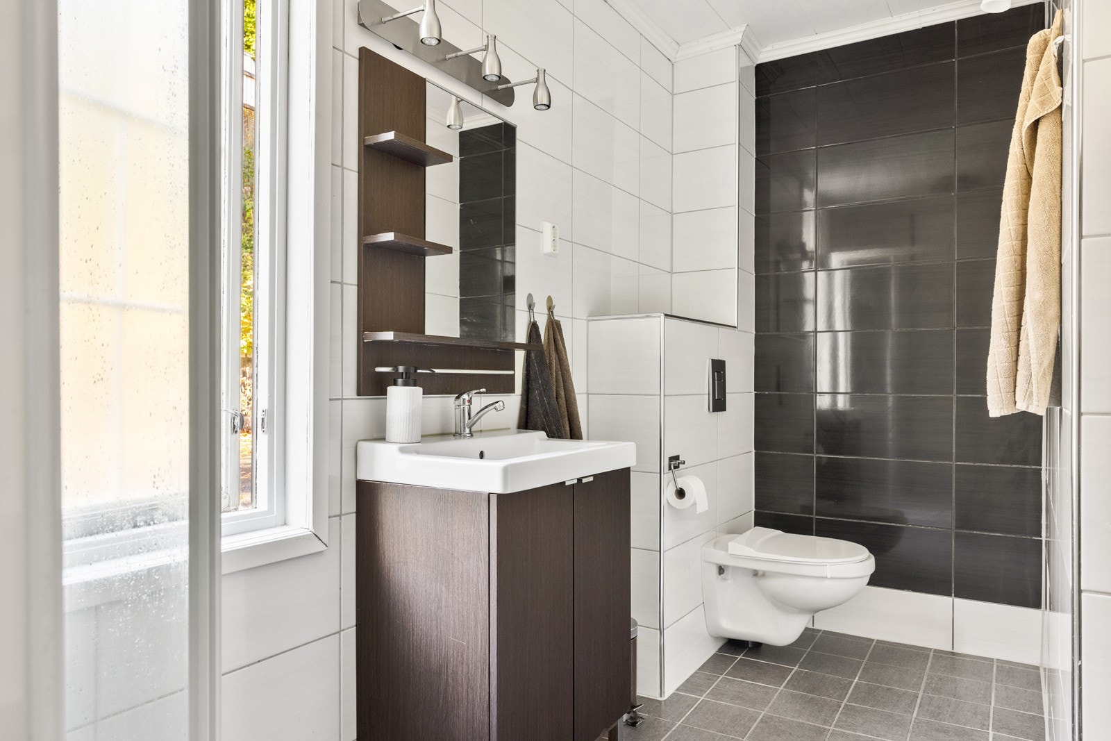 Badet ble oppgradert i 2010 og er helfliset meg gulvvarme. Badet er innredet med baderomsmøbel, speil med lys, dusjkabinett og vegghengt toalett. Galleribilde