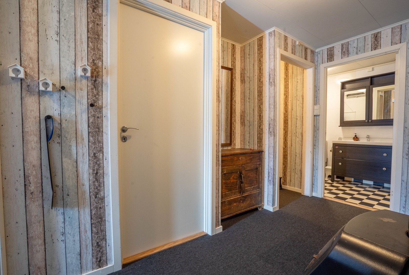 Hall med kubbebrenner, inngang til bad og soverom 2 samt garderobehjørne Galleribilde