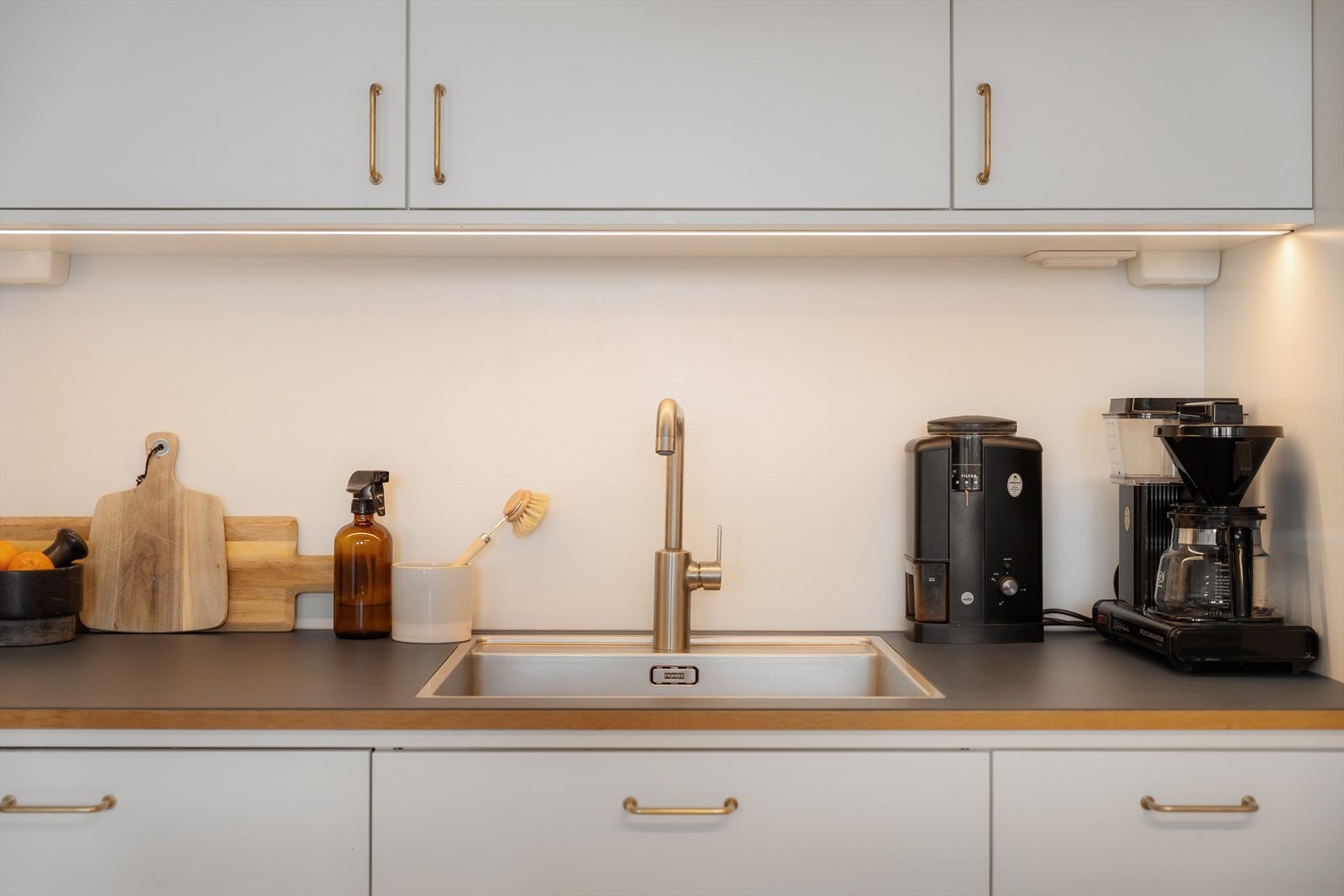 Belysning under overskap og linoleum benkeplate med planlimt kum i rustfritt stål Galleribilde