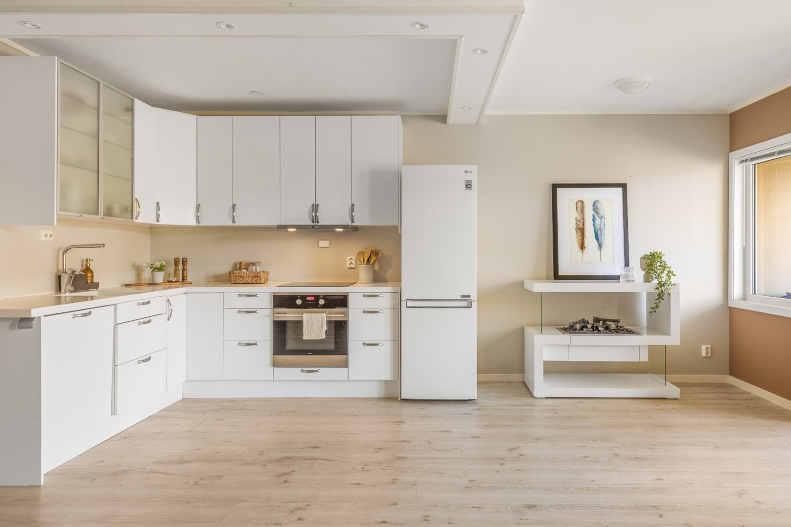 En åpen løsning mellom stue og kjøkken som bidrar til flere sosiale soner selv ved matlaging Galleribilde