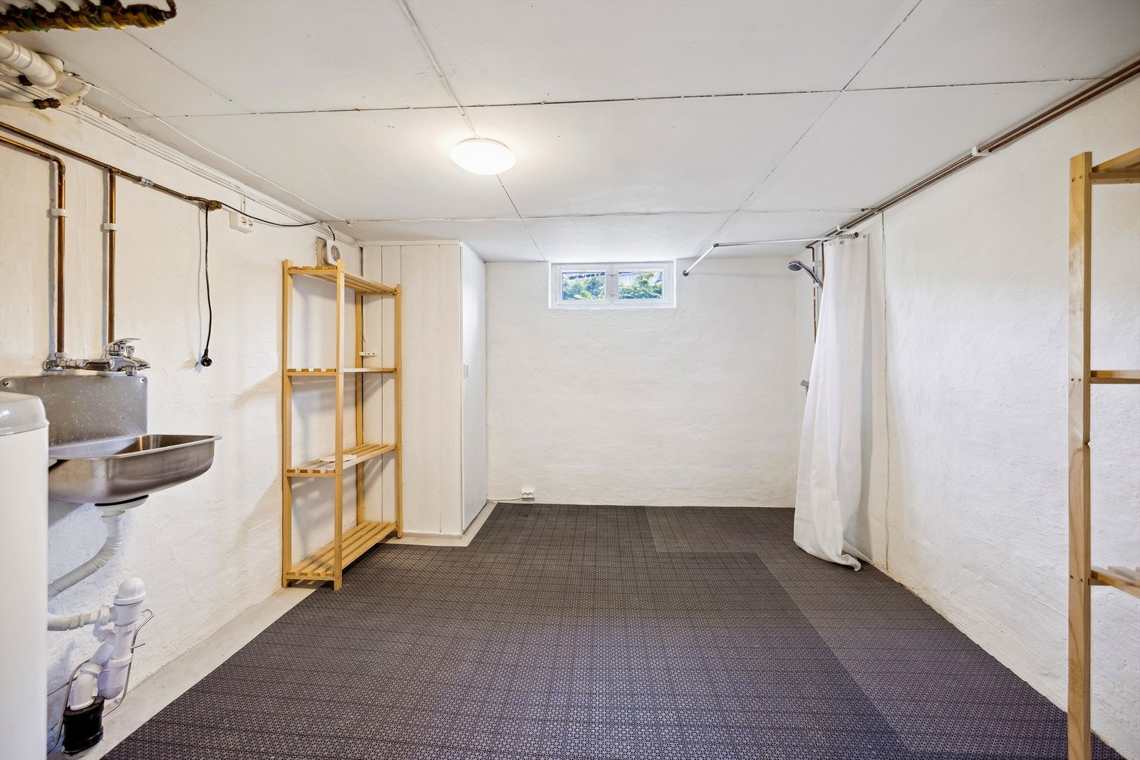 Det er anlagt vaskerom i kjeller med oppvaskkum i metall, opplegg for vaskemaskin, 2 gulvsluk og åpen dusjløsning på vegg. Mekanisk avtrekk via yttervegg, tilluft via åpen dør og vv bereder på ca. 200 liter med hovedstoppekran. Galleribilde