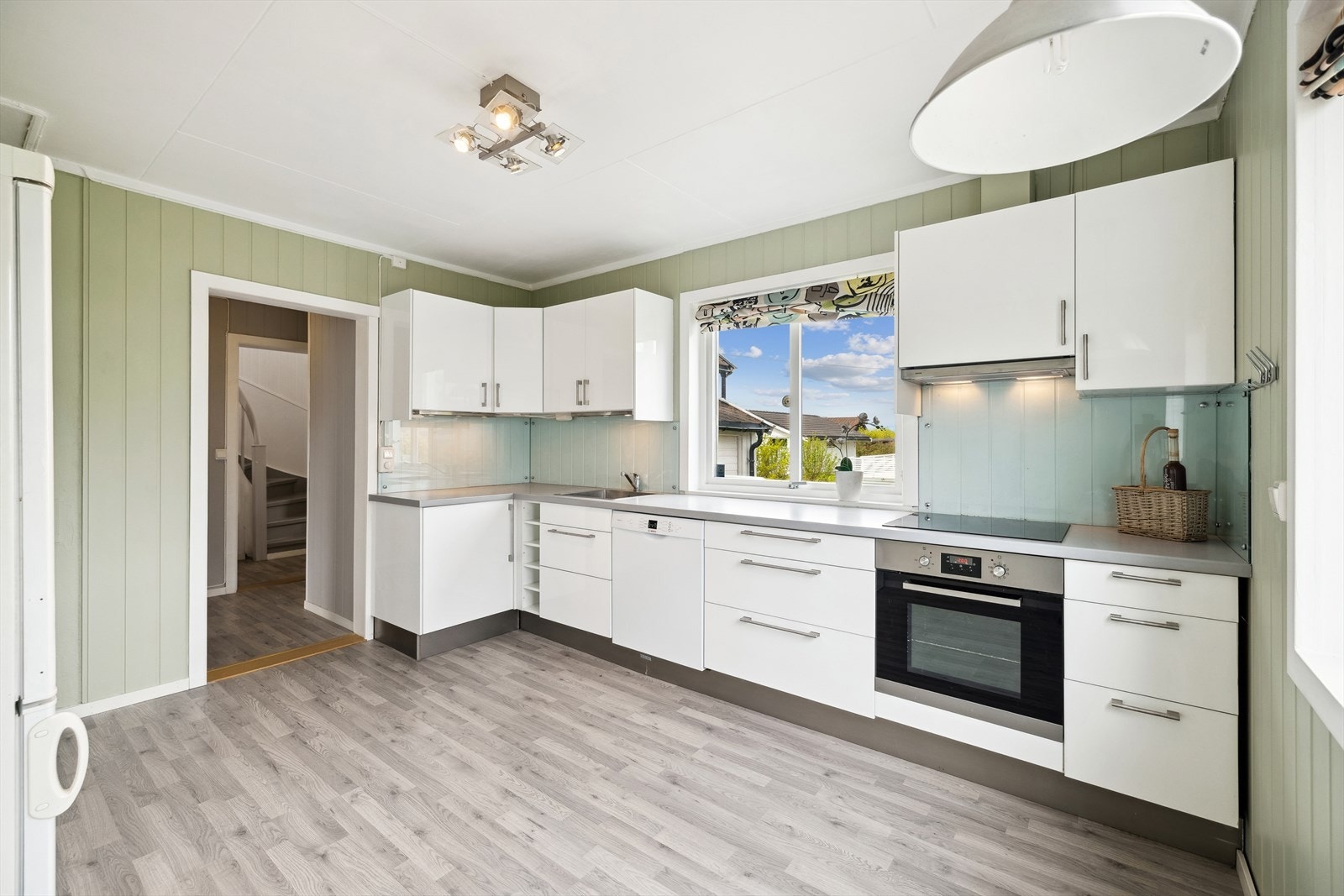 Kjøkkenet har laminerte fronter og skuffer med demping, laminerte benkeplater, veggflater over kjøkkenbenker med glassplate og oppvaskkum i metall. Galleribilde