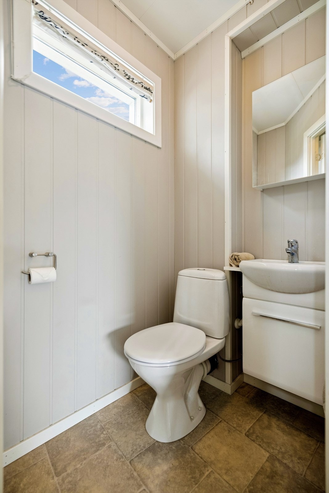 Toalettrom i 1. etasje har gulvmontert toalett og servant i innredning på vegg. Det er belegg på gulv, malt panel på vegg og malte plater i himling. Naturlig ventilasjon via åpningsbart vindu og tilluft via spalte under dørblad. Galleribilde