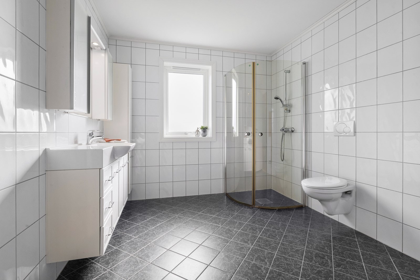 Badet er også av god storleik og innreidd med dusjhjørne, servant i underskap, høgskap og vegghengt klosett Galleribilde