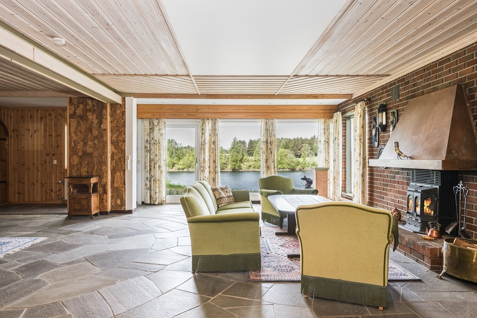 Stor kjellerstue med steinfliser på gulv og peis med peisinnsats. Galleribilde