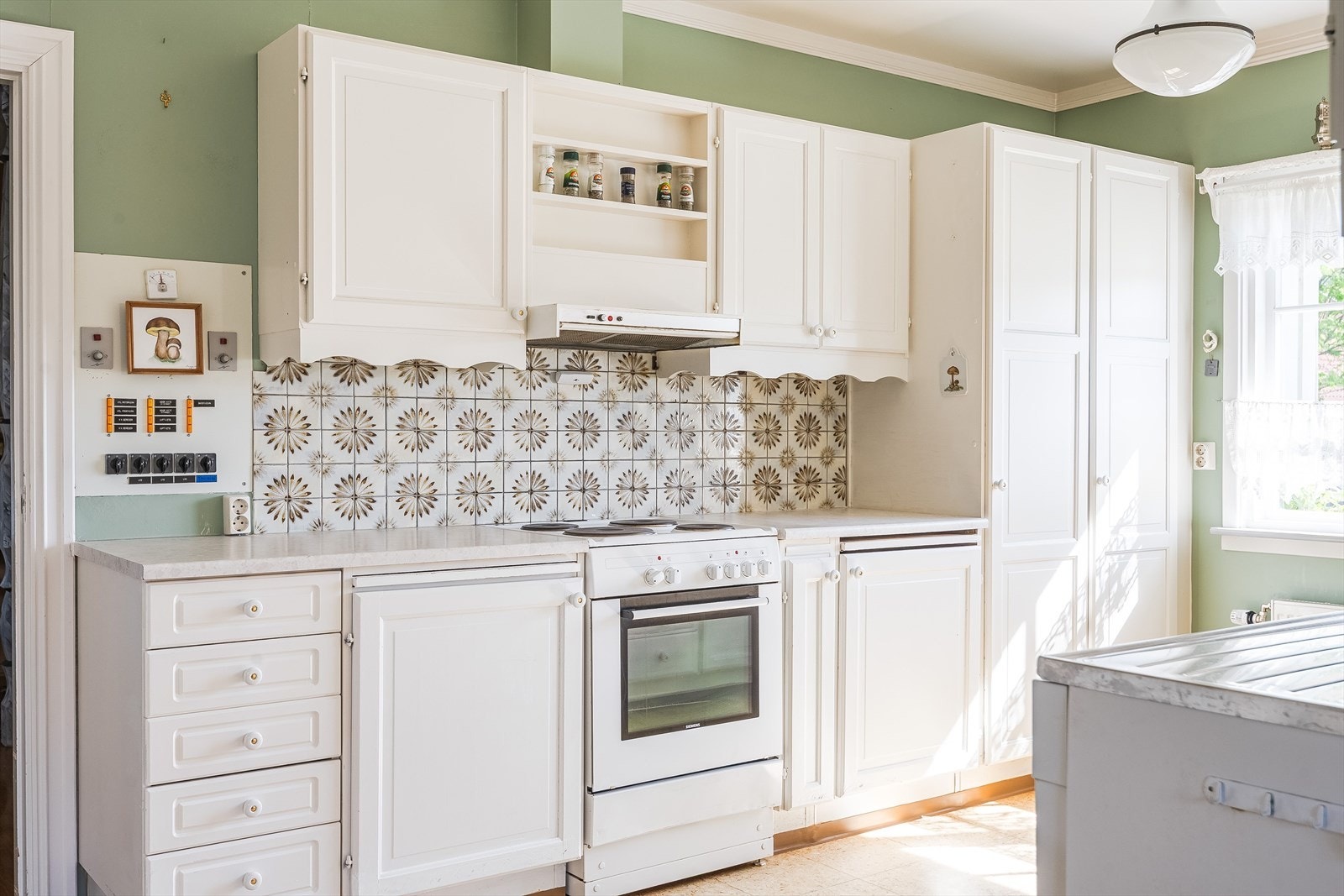 Innredningen har lyse profilerte fronter, laminert benkeplate, benkebeslag med nedfelt oppvaskkum og fliser i benkeryggen. Galleribilde