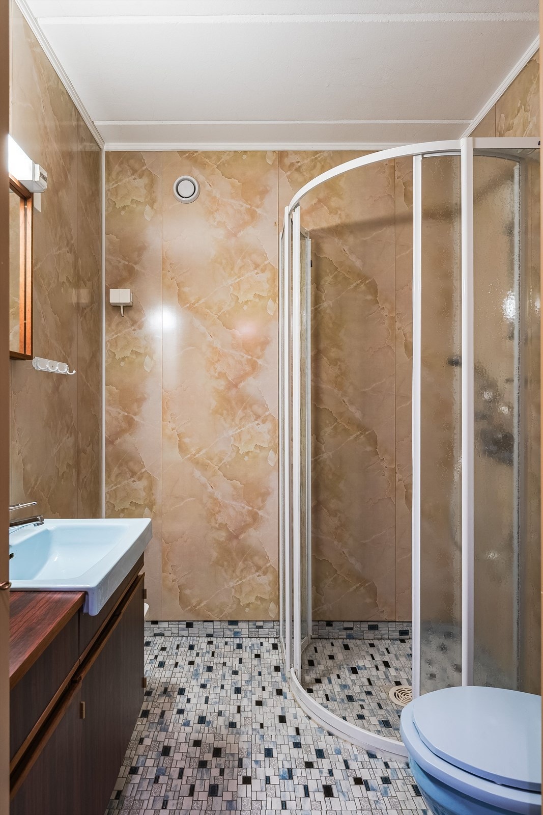 Eldre baderom i hybeldelen med mosaikkfliser på gulv, elektriske varmekabler og våtromsplater på veggene. Galleribilde