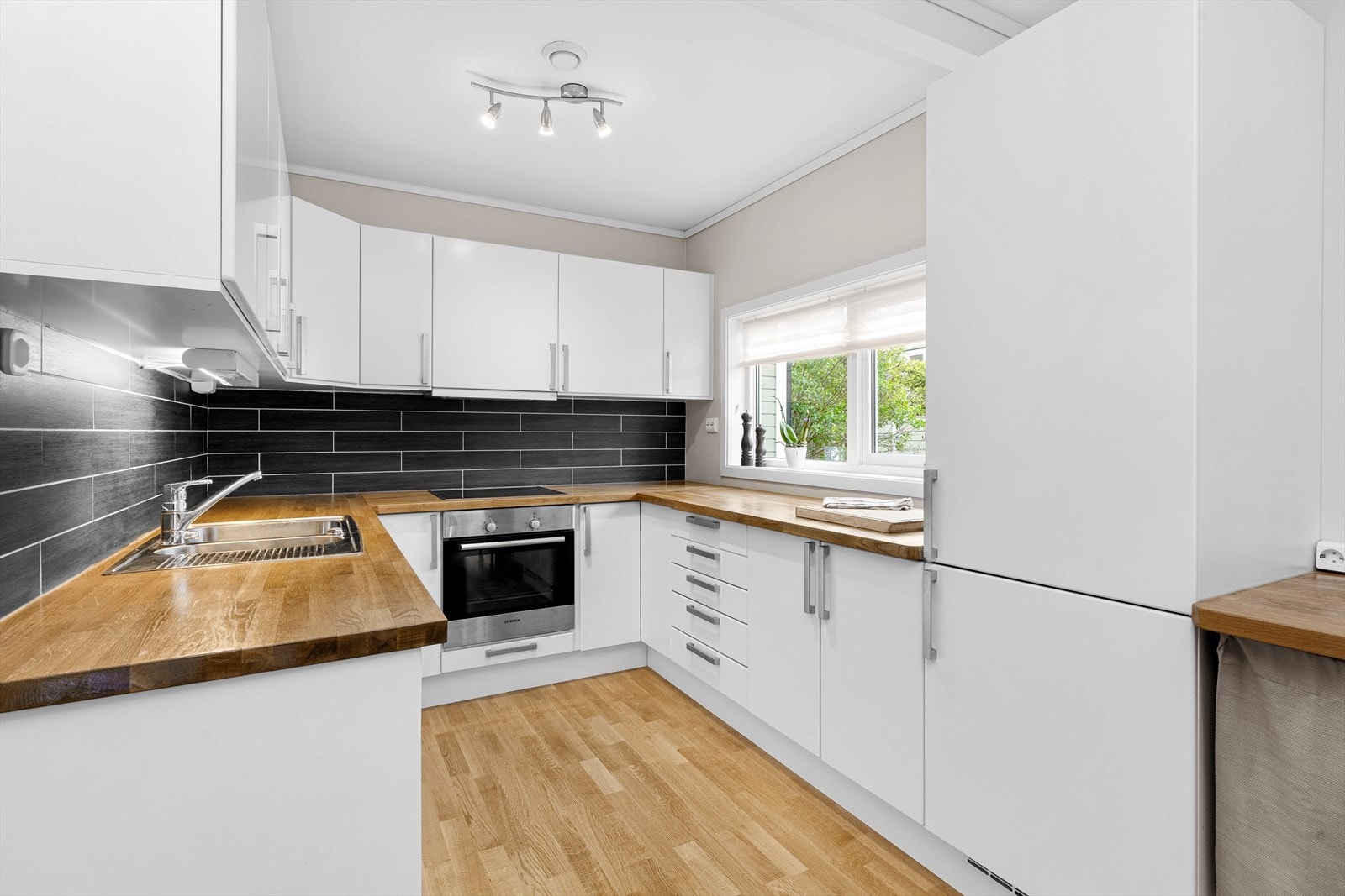 Boligen har et lyst og tidløst kjøkken med slette fronter. Galleribilde