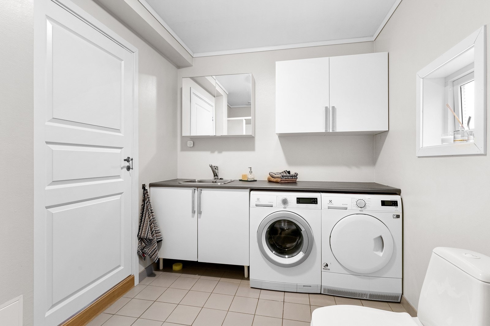 Rommet er innredet med benkeplate og servant, samt opplegg for vaskemaskin og tørketrommel. God benkeplass gir praktisk arbeidsflate til klesvask. Galleribilde