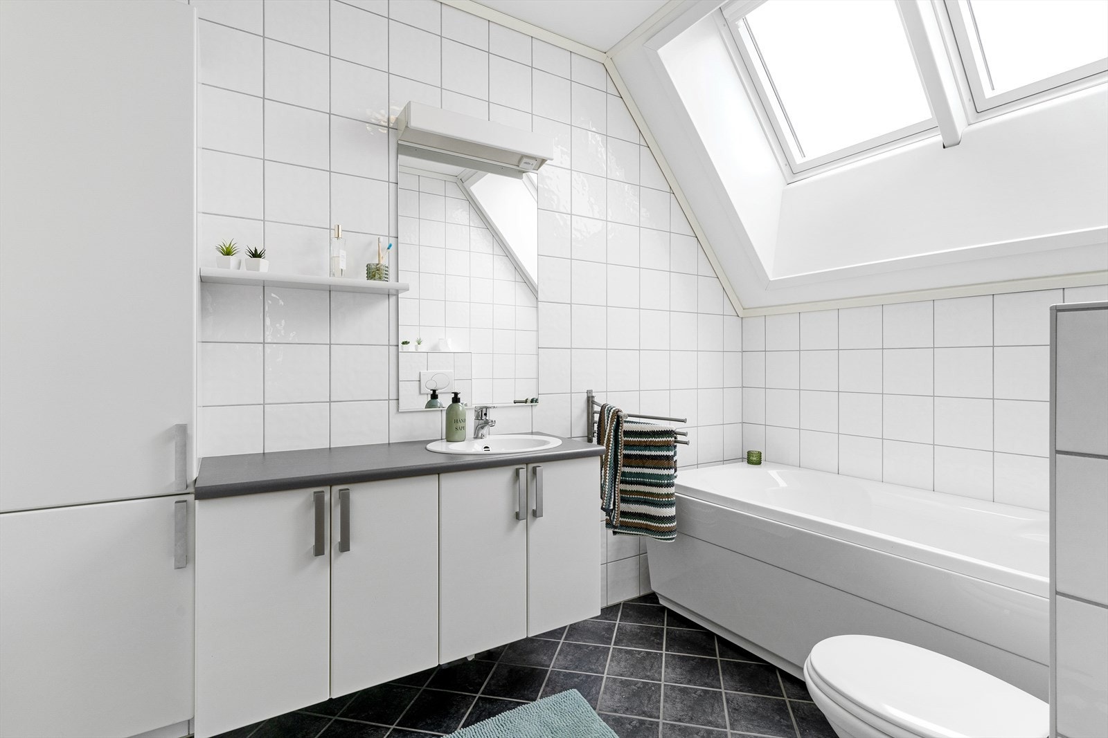 Badet i 2. etasje er lyst og pent innredet med flislagte overflater, servant på baderomsinnredning med underskap og høyskap. Galleribilde