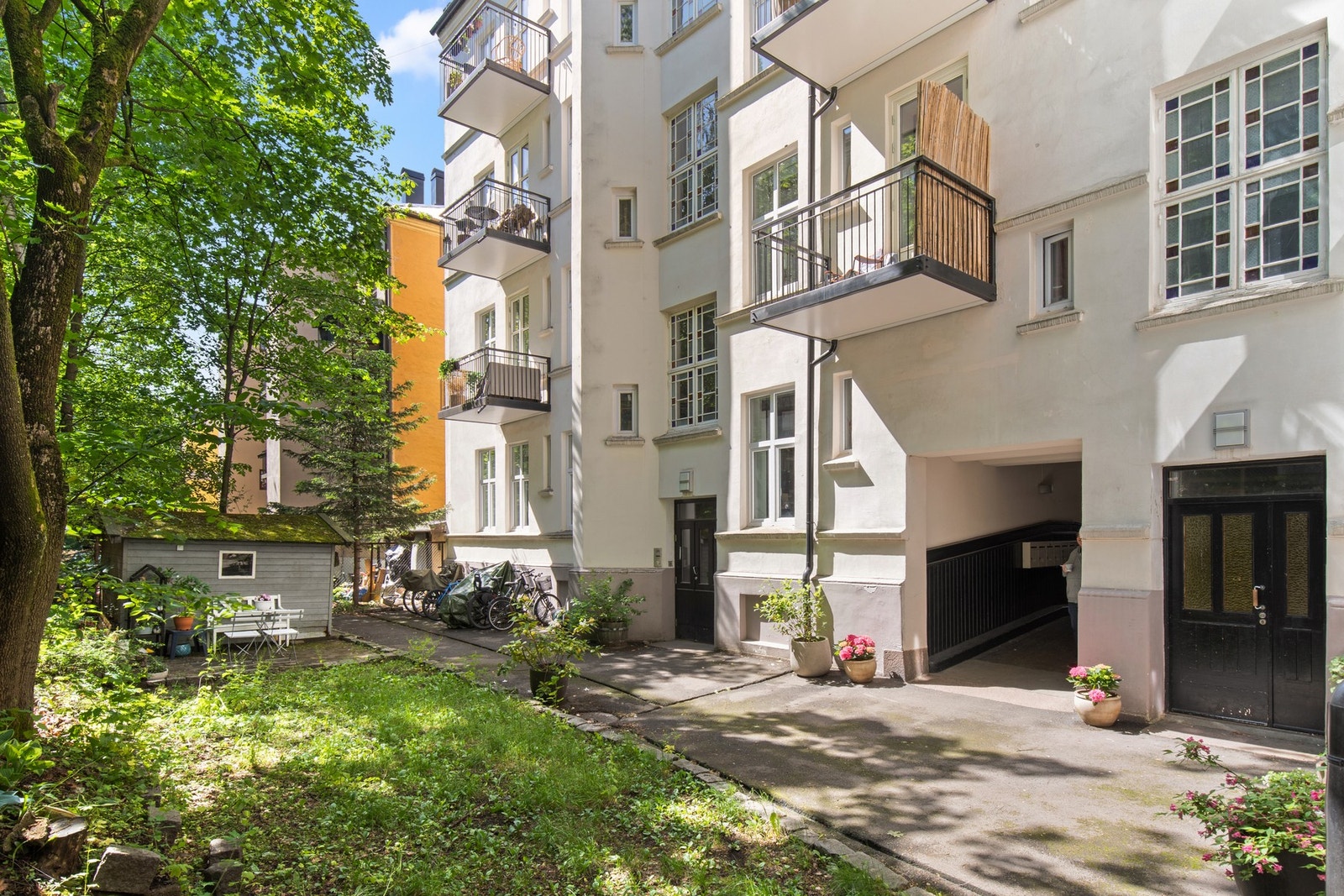 I bakgården er det asfalterte arealer, gressplen, sittegruppe, sykkelparkering og variert beplantning. Galleribilde