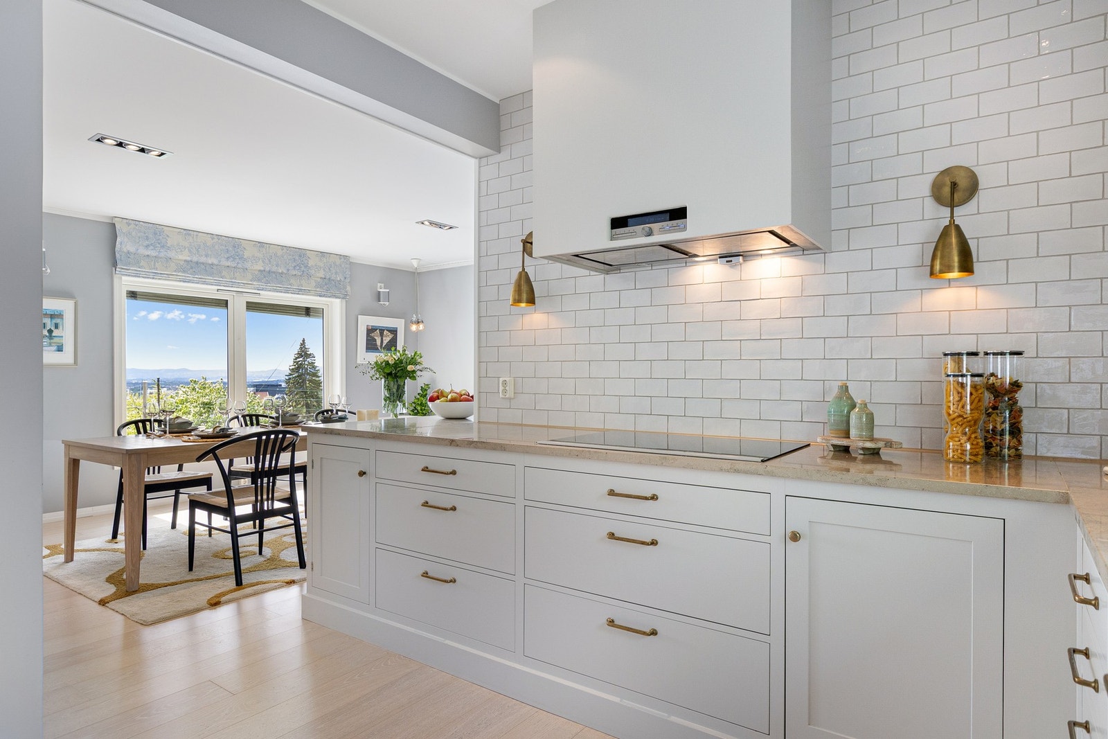 Det er fliser på vegg over benkeskap på én side og montert komfyrvakt. Galleribilde