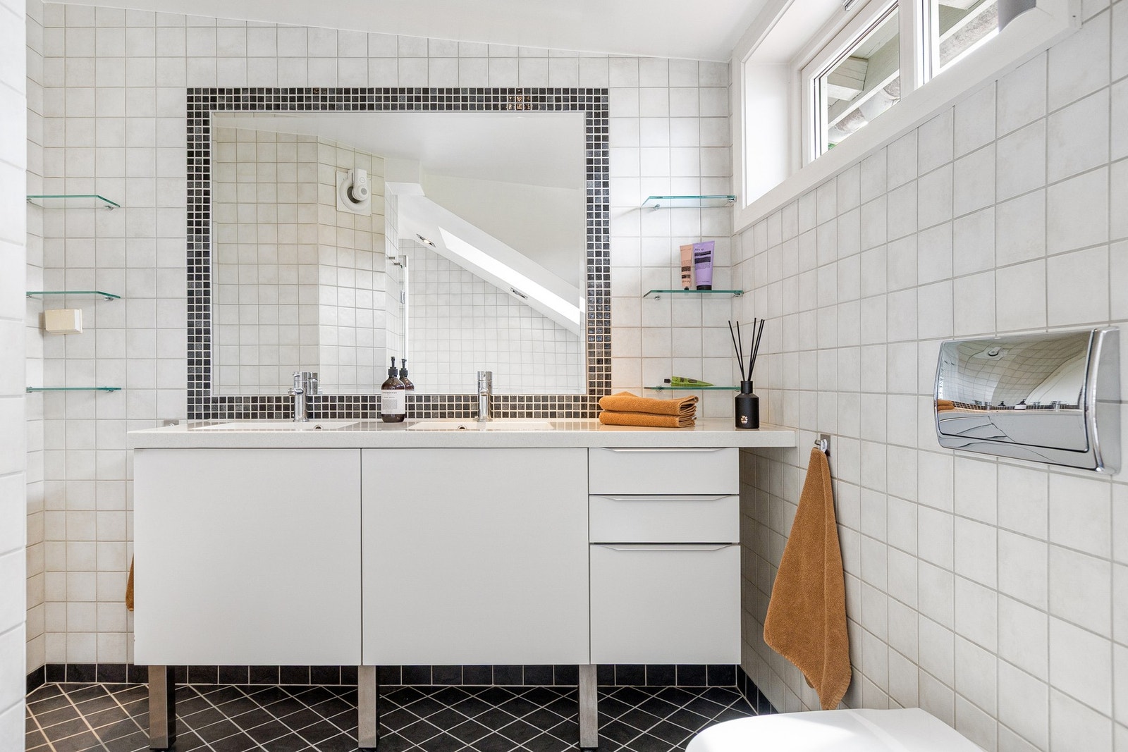 Innredningen består av dobbeltservant i helstøpt plate, veggmontert toalett og innfliset speil. Galleribilde