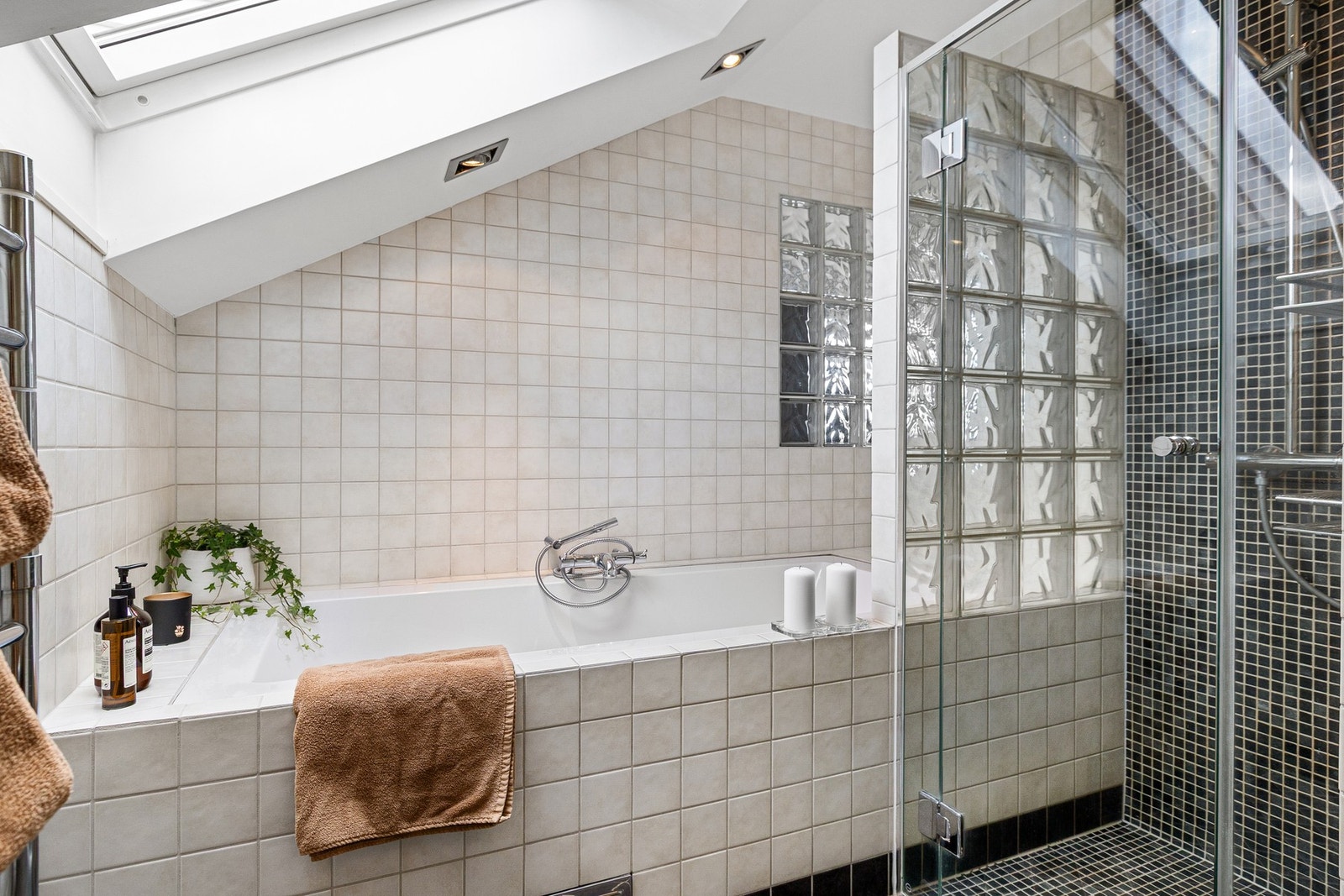 Videre er det dusj med innfellbare glassdører og eget badekar omkranset av glassbyggerstein. Galleribilde