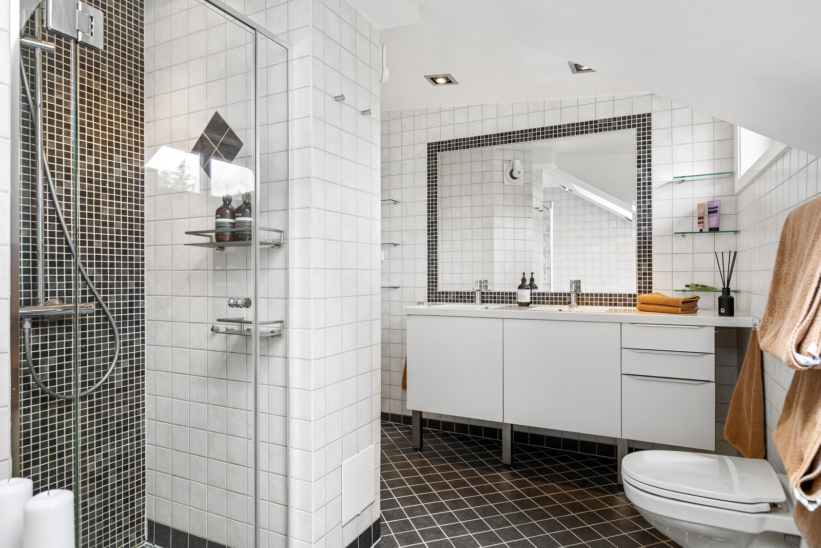 Delikat bad med flislagt gulv med varmekabler, flislagte overflater og mosaikkfliser i dusjsonen. Galleribilde