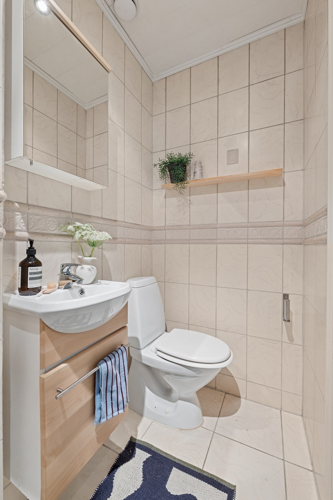 Flislagt baderom med toalett, servant, speilskap og dujløsning. Galleribilde