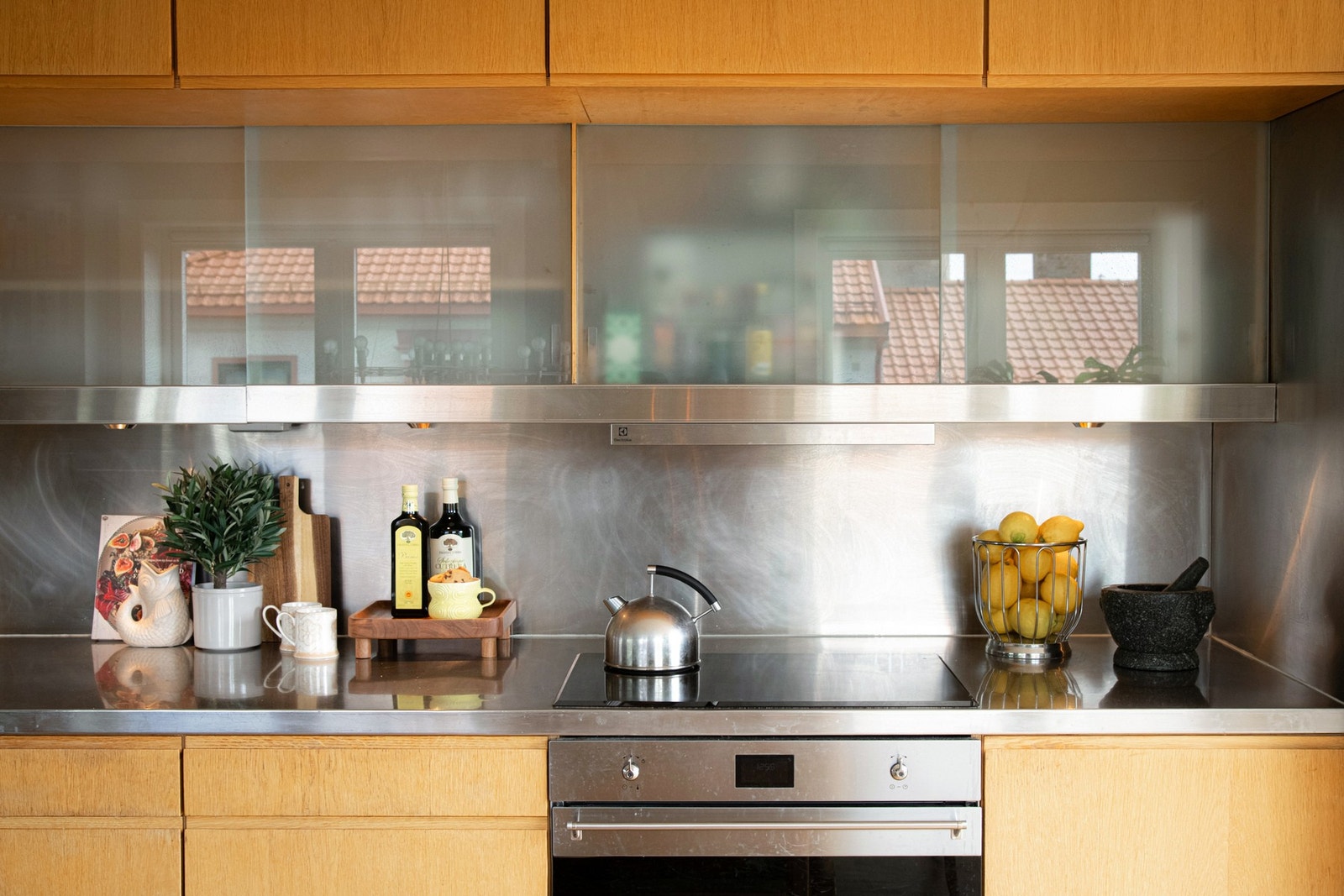 Kjøkkenet er skreddersydd og snekkerbygd etter arkitekttegning fra 2000, med benkeplate og veggfelt i rustfritt stål som gir et helhetlig og gjennomført designuttrykk. Galleribilde