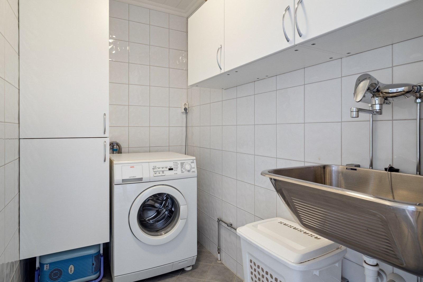 Flislagt vaskerom med varme i gulv. Rommet har innredning med skap og utslagsvask, samt opplegg for vaskemaskin. Galleribilde