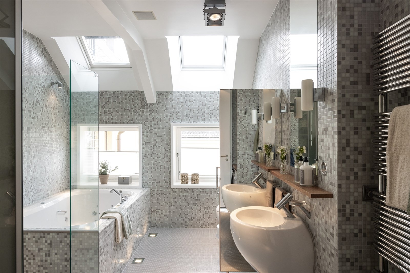 Flislagt baderom med dusj, badekar, to servanter samt opplegg for vaskemaskin og tørketrommel. Galleribilde