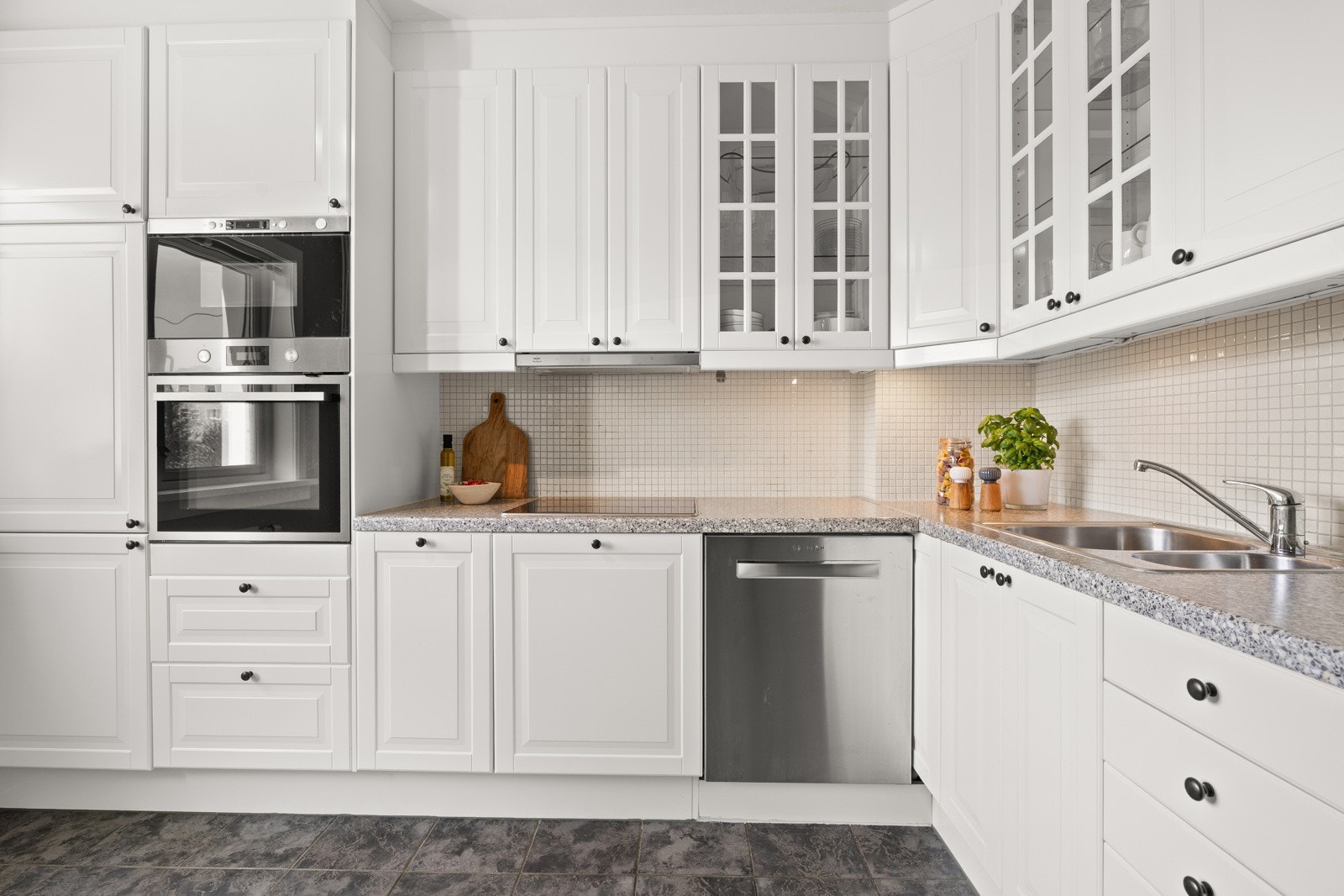 Stilrent og tidløst kjøkken bestående av innredning med hvite profilerte fronter på skuffer og skapdører. Galleribilde