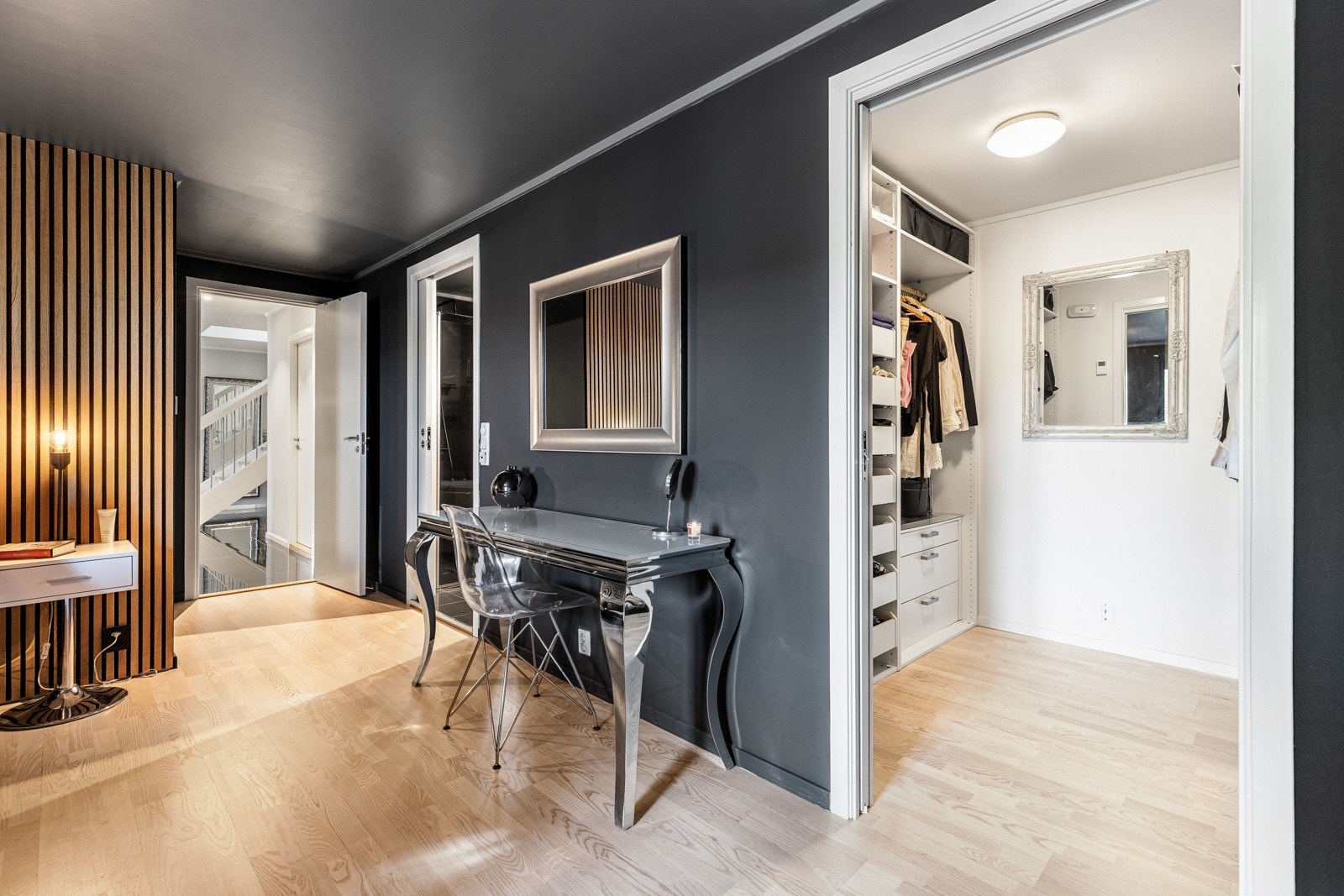 Rom med mørke vegger, lyst gulv, og innebygget walk-in closet. Sminkebord med speil. Galleribilde