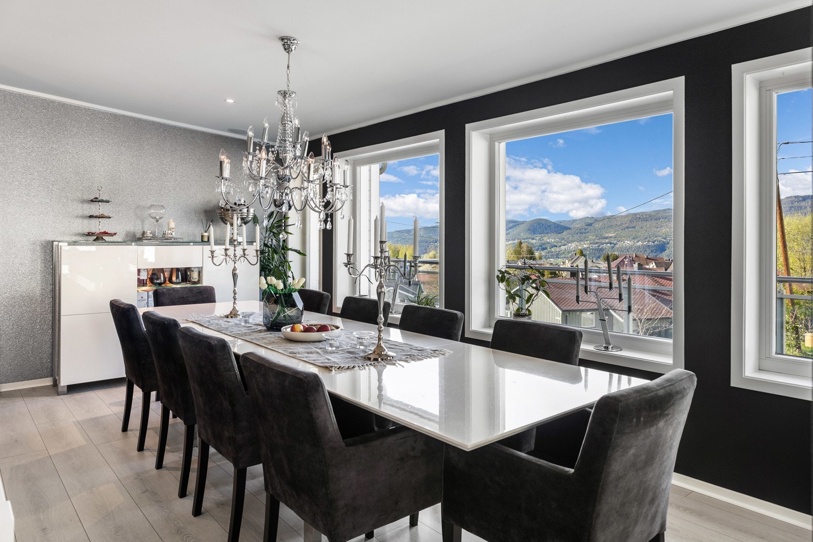 Spisestue med stort spisebord, lysekrone og store vinduer som gir utsikt mot fjell og natur. Galleribilde