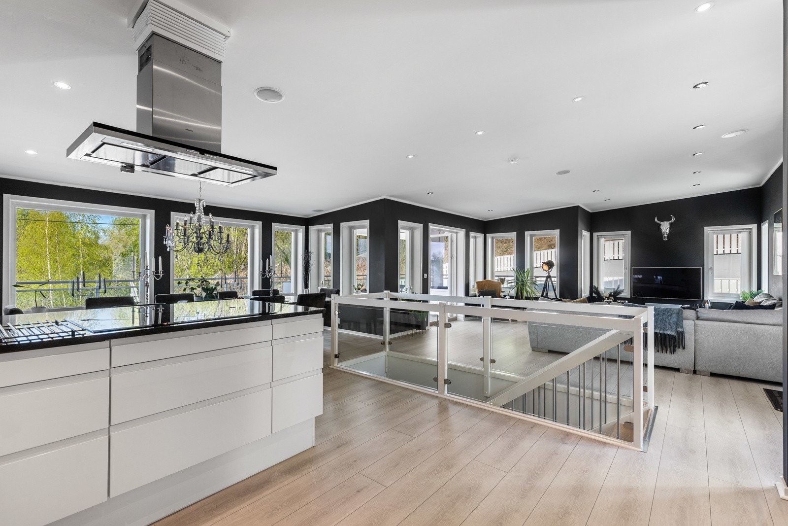 Lys og moderne stue med åpen kjøkkenløsning, store vinduer og god plass til møblering. Galleribilde