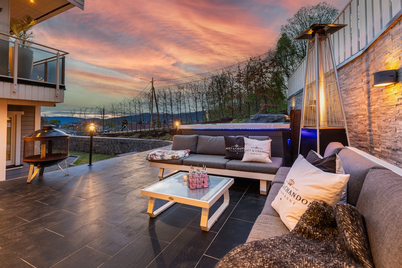 Uteområde med sittegruppe, peis og varmelampe. Flott utsikt over landskapet under en vakker solnedgang. Galleribilde