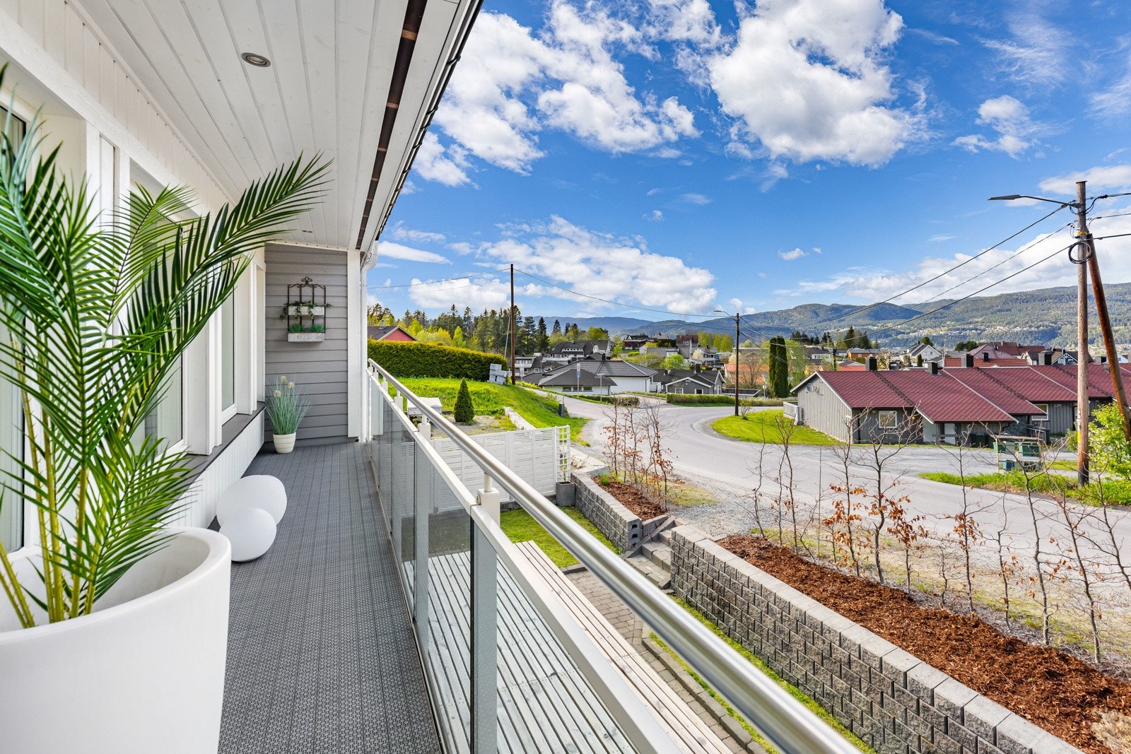 Balkong med glassrekkverk og utsikt mot nabolaget og åser. Galleribilde