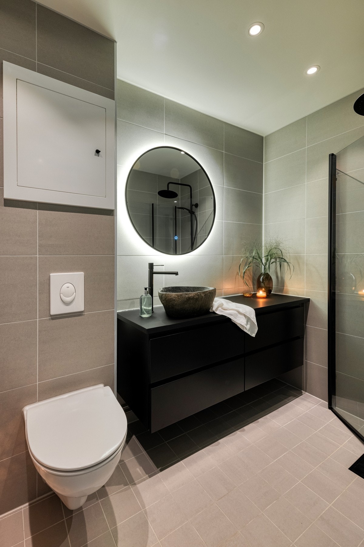 På badet er det baderomsinnredning bestående av benkeskap med glatte fronter med ovenpåliggende servant og speil med lys rundt over. Galleribilde