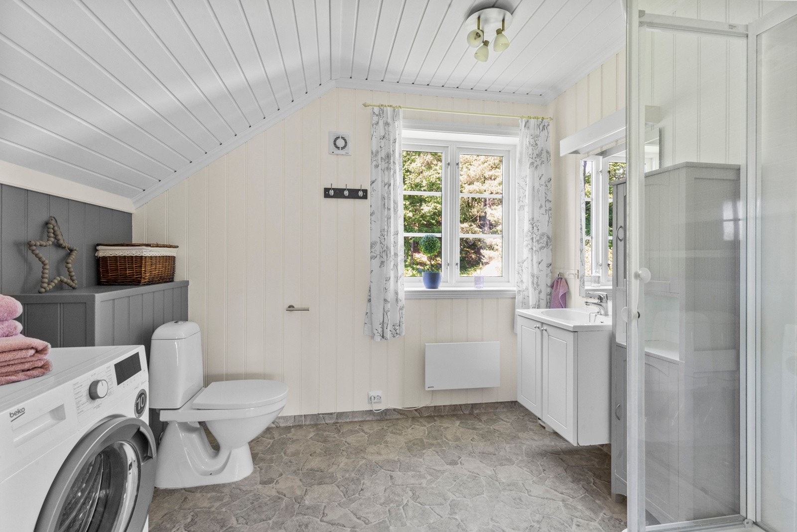 På badet er det gulvstående toalett, dusj, servant og speil. Galleribilde