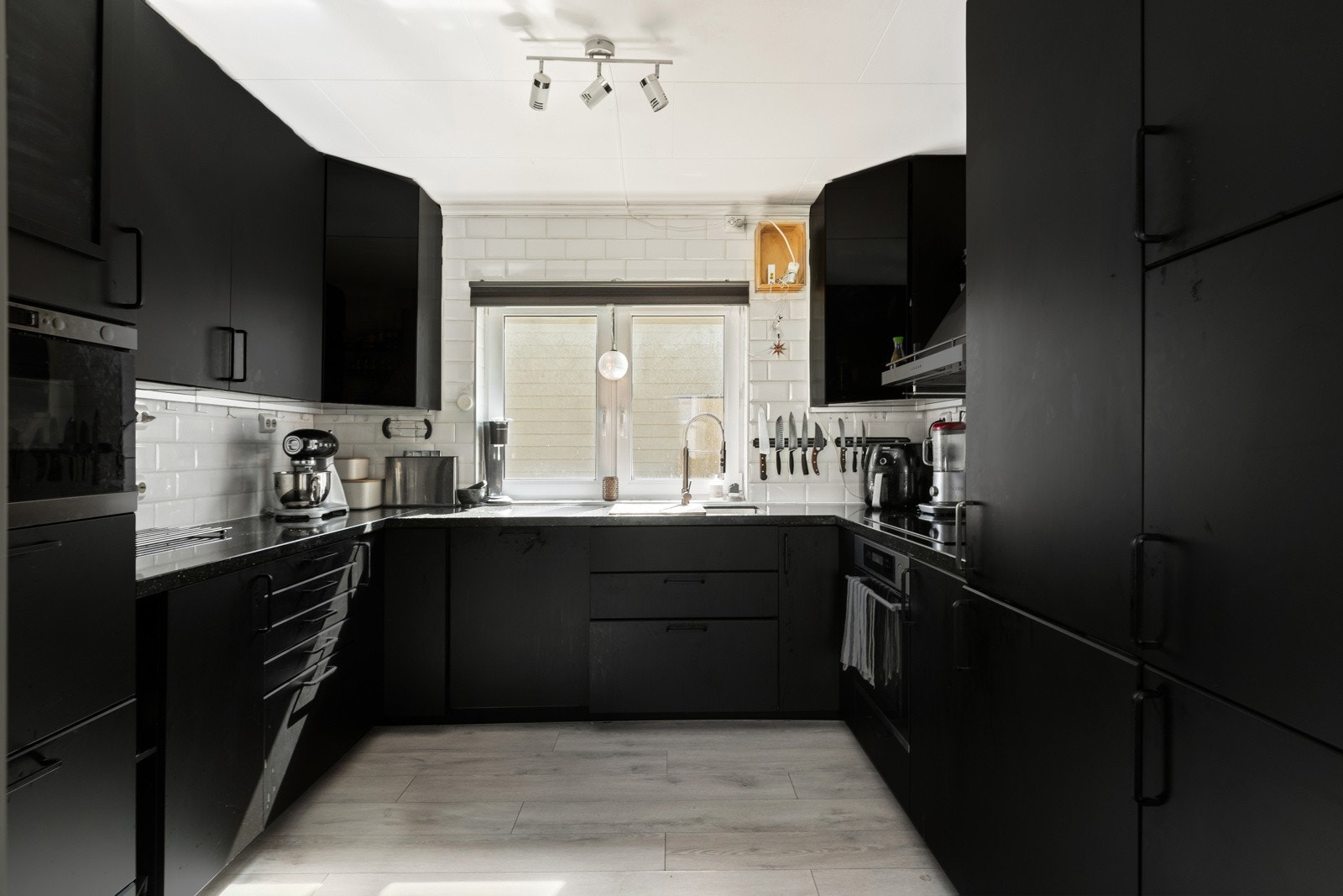 Kjøkken med glatte fronter, laminat benkeplate og fliser over benkeplaten. Galleribilde